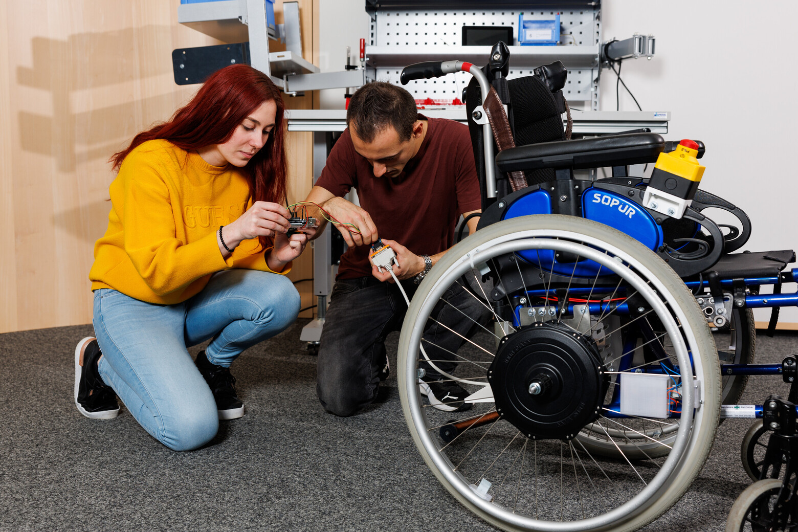 Eine Studentin und ein Student kümmern sich um die letzten technischen Details und verbinden Kabel miteinander. 