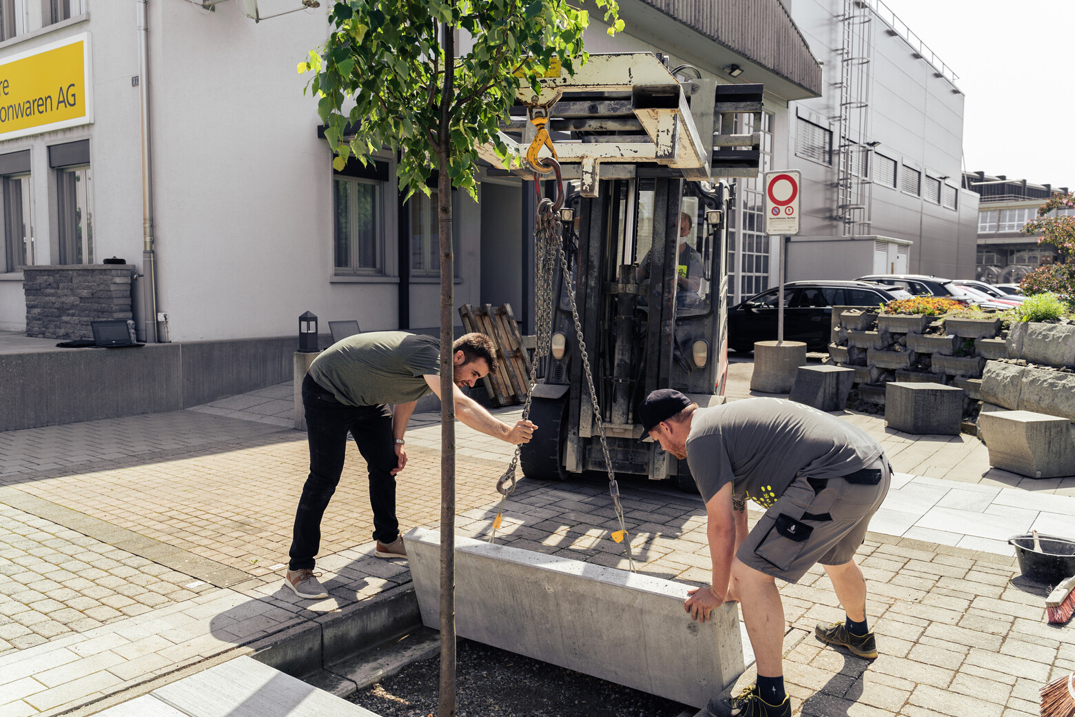 Die Installation der intelligenten Baumgrube übernehmen drei Männer, wobei auch ein Frontstapler zum Einsatz kommt.