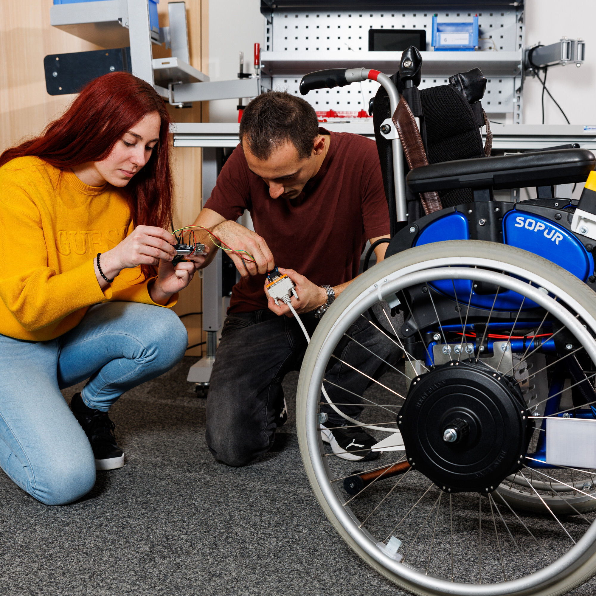 Eine Studentin und ein Student kümmern sich um die letzten technischen Details und verbinden Kabel miteinander. 