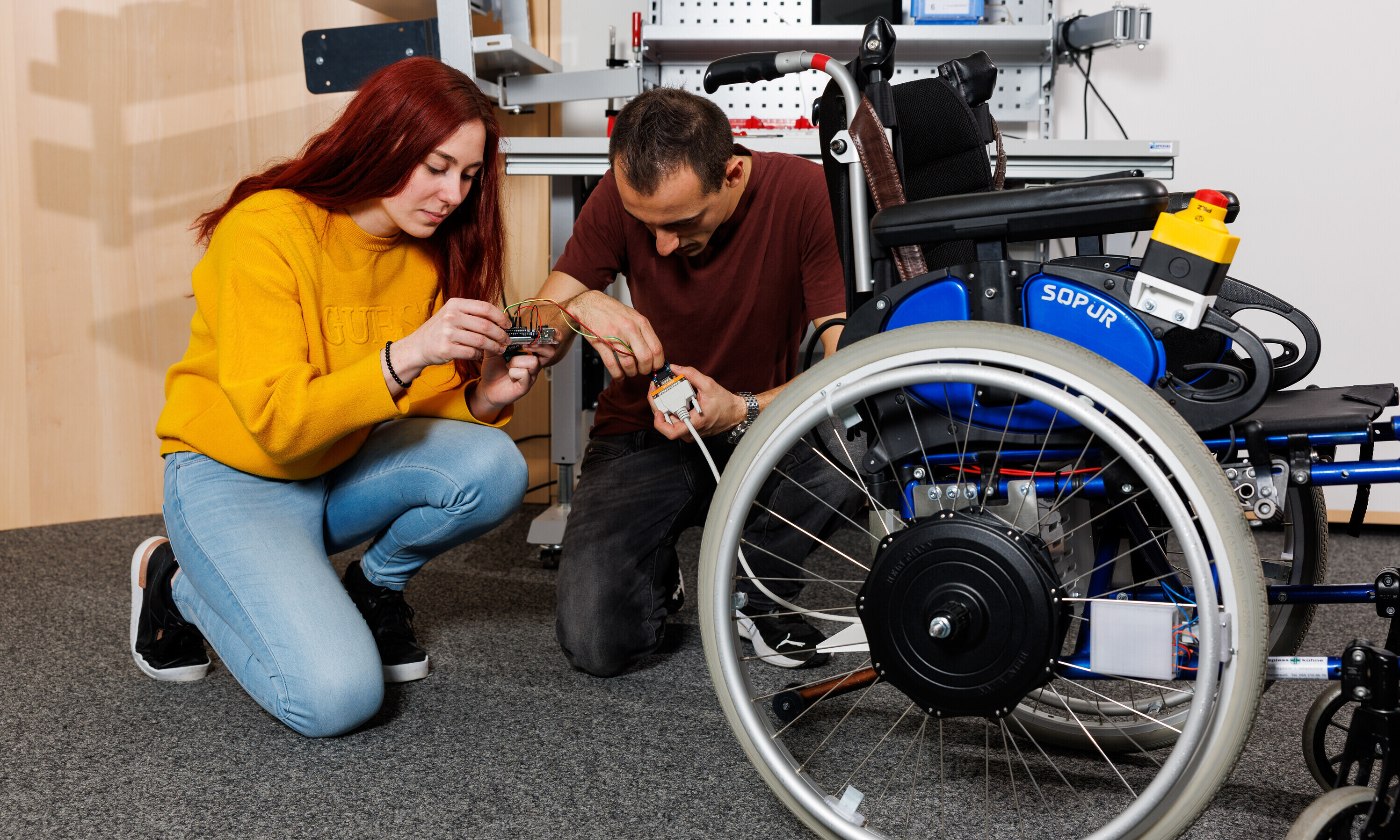 Eine Studentin und ein Student kümmern sich um die letzten technischen Details und verbinden Kabel miteinander. 