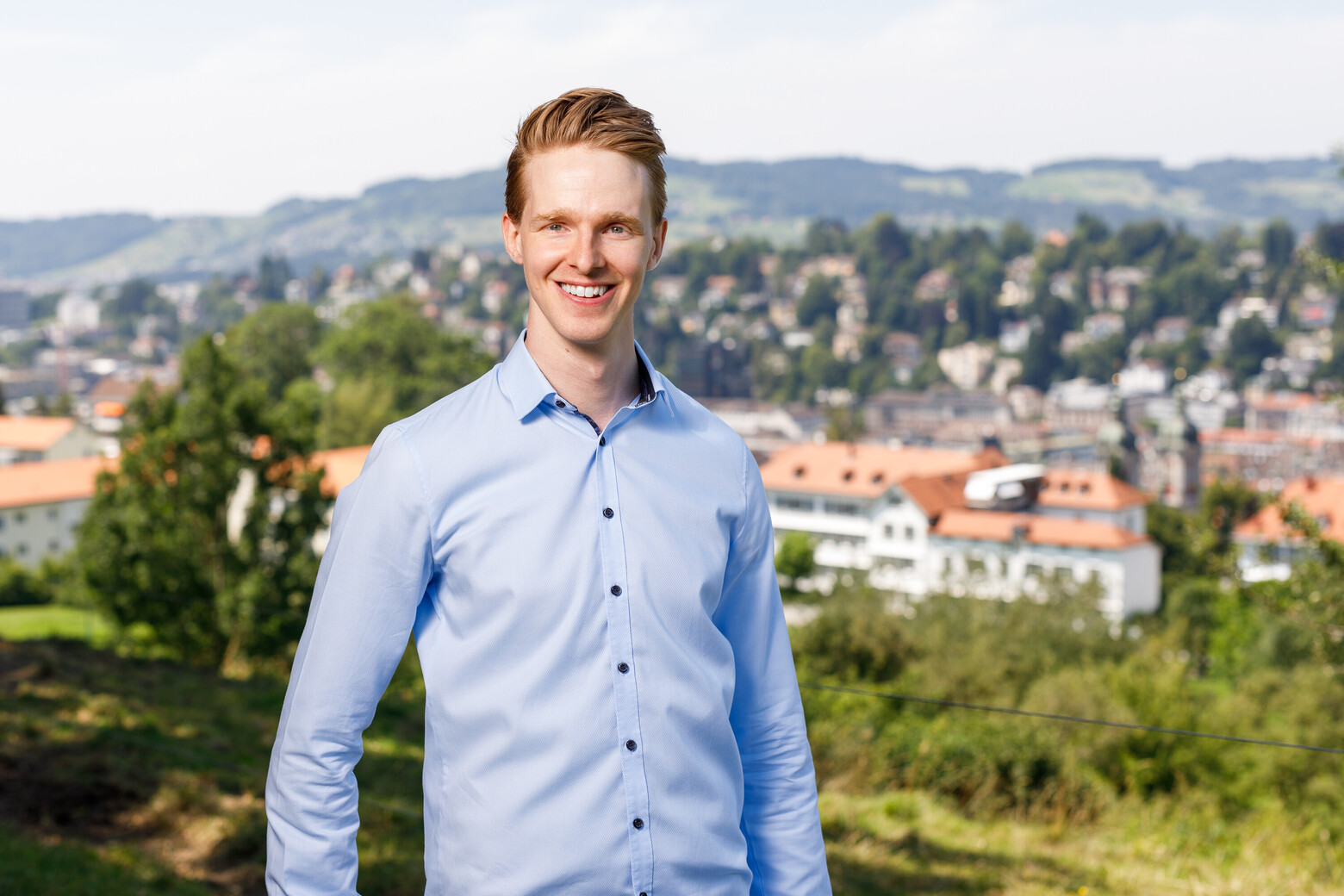 Das Porträt zeigt Lars Bittel in einem hellblauen Hemd; er steht draussen, im Hintergrund ist die Stadt zu sehen.