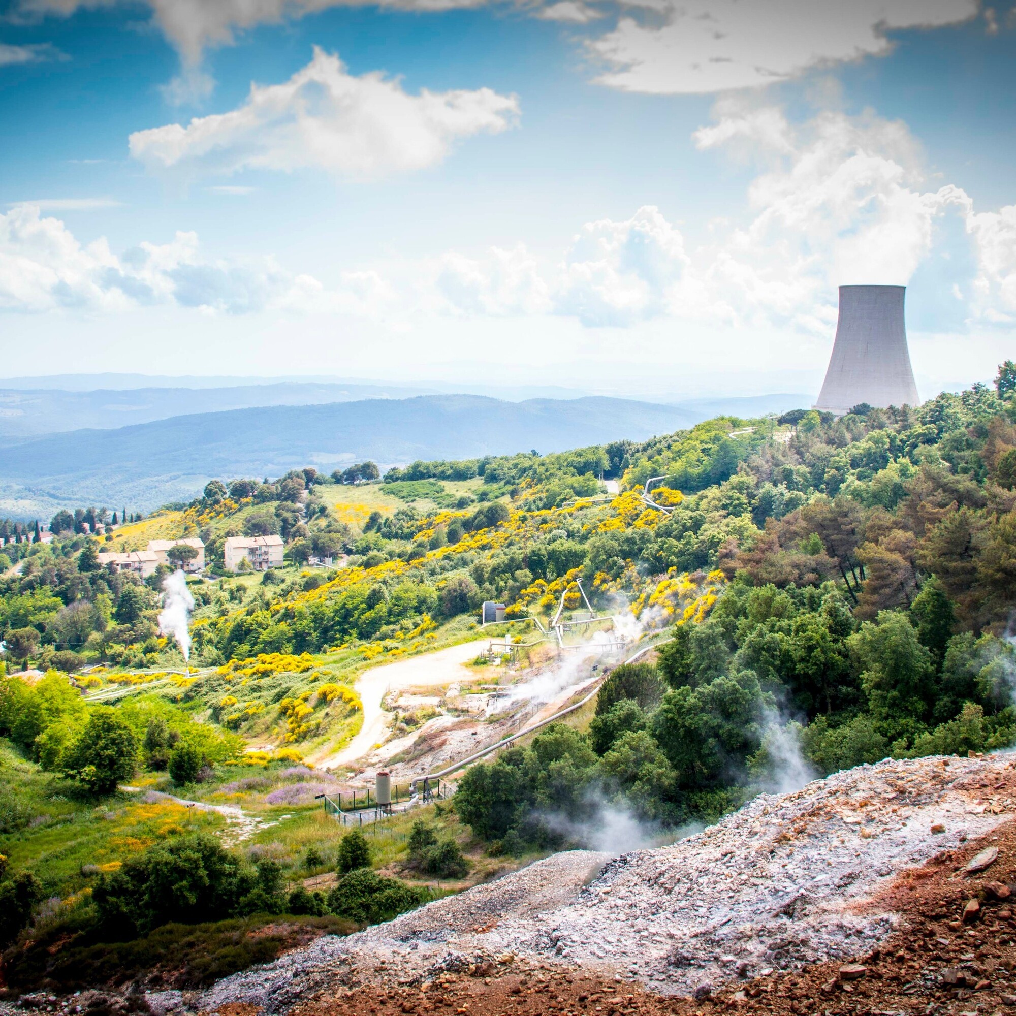 Auf dem Bild sieht man eine Landschaft zwischen Wald und Steinbruch, und im Hintergrund einen Kühlturm eines Atomkraftwerks.