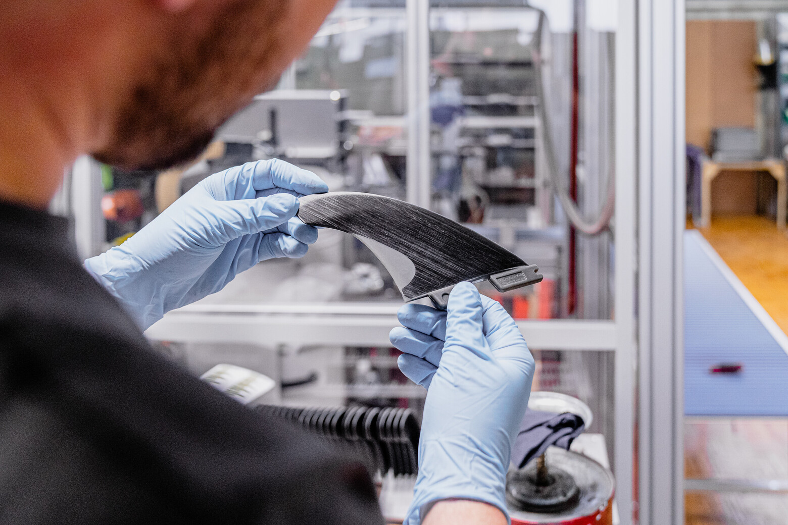 Auf dem Bild ist eine fast fertige Surffinne in den Händen des Produzenten zu sehen.