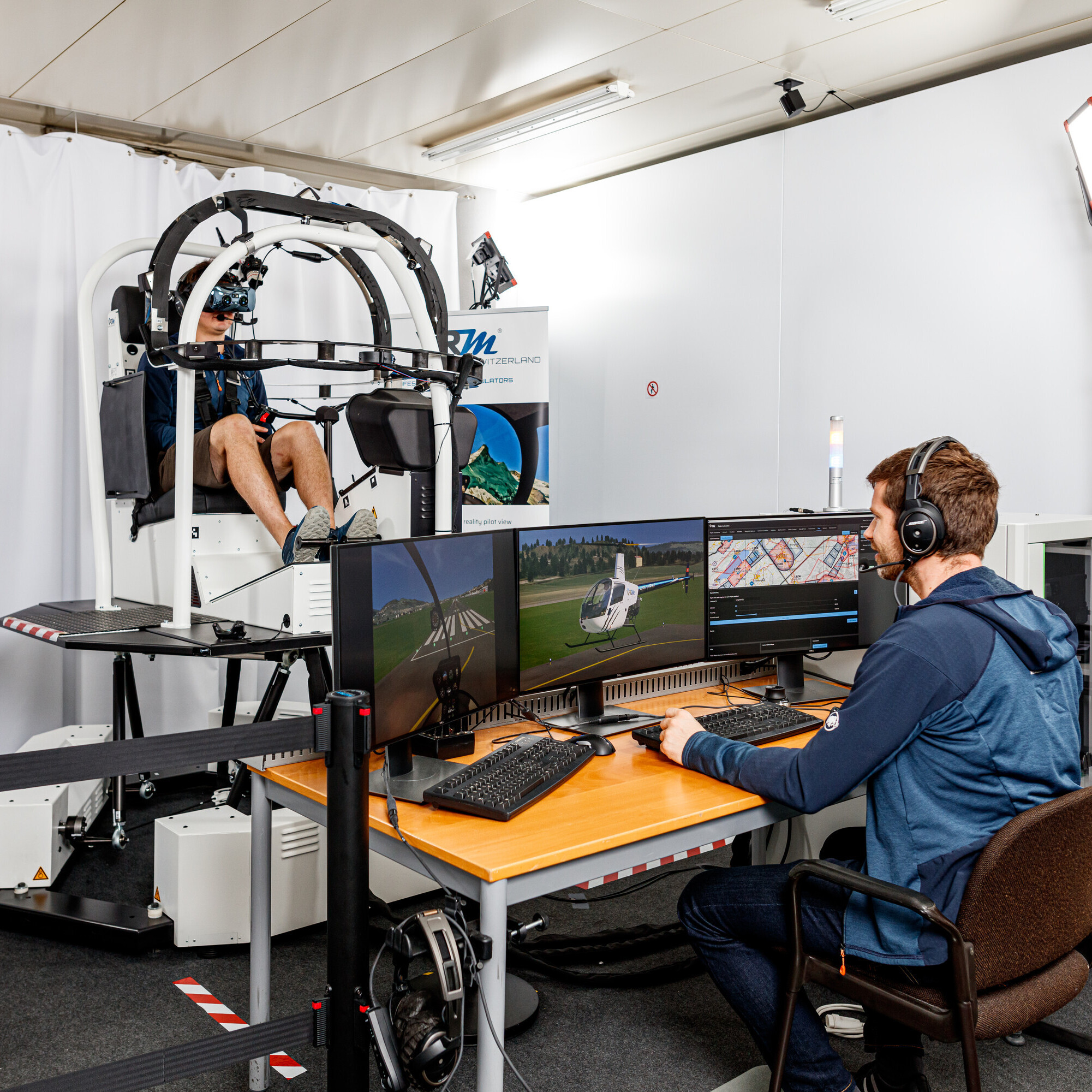 Ein Flugsimulator der VRMotion AG wird auf Herz und Nieren geprüft: Ein Mann sitzt im Simulator, ein weiterer vor mehreren Bildschirmen.