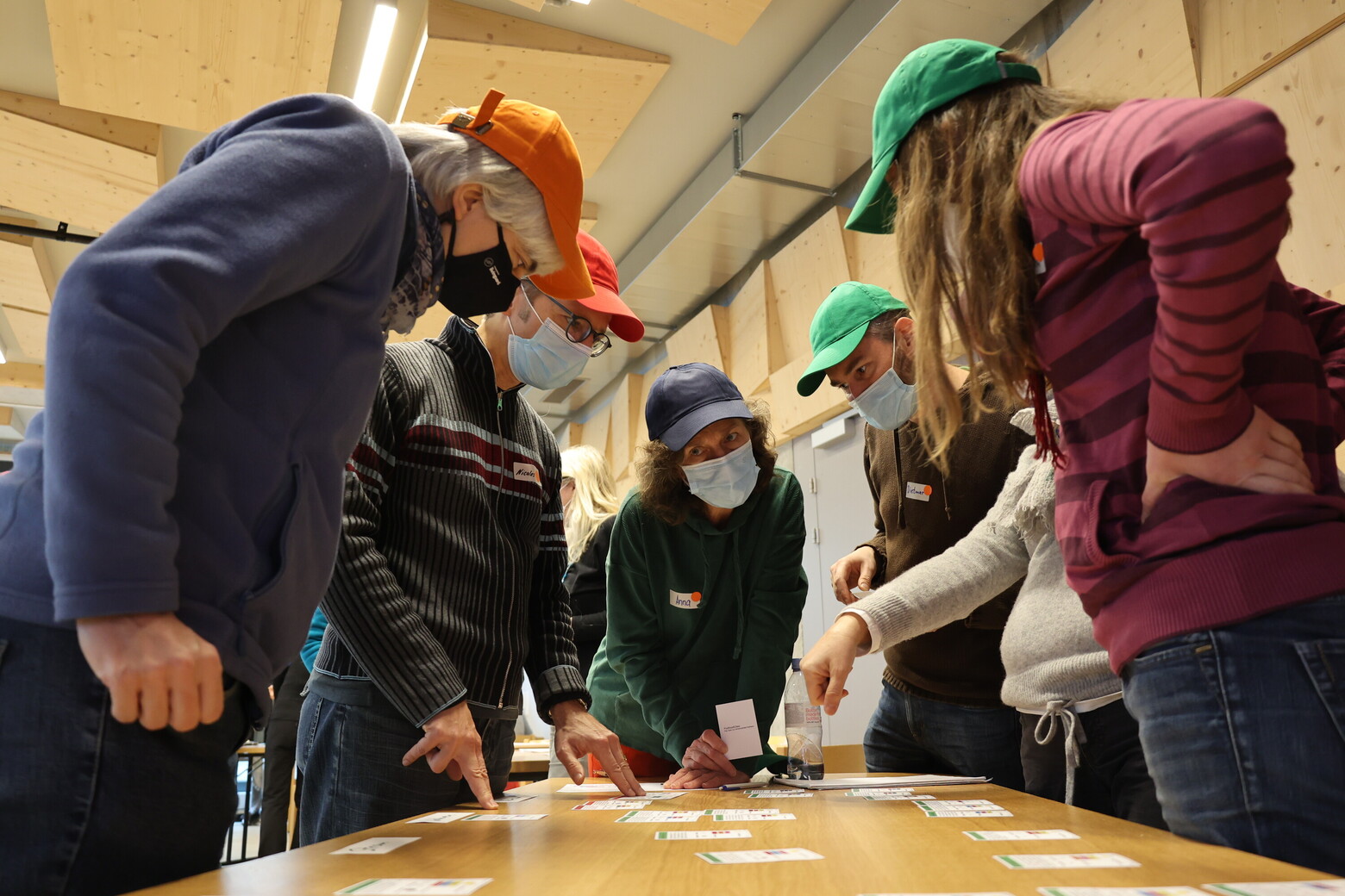 Hier verhandeln die Akteure mit Schutzmasken, vor ihnen liegen verschiedene Inputs der Bevölkerung auf dem Tisch.