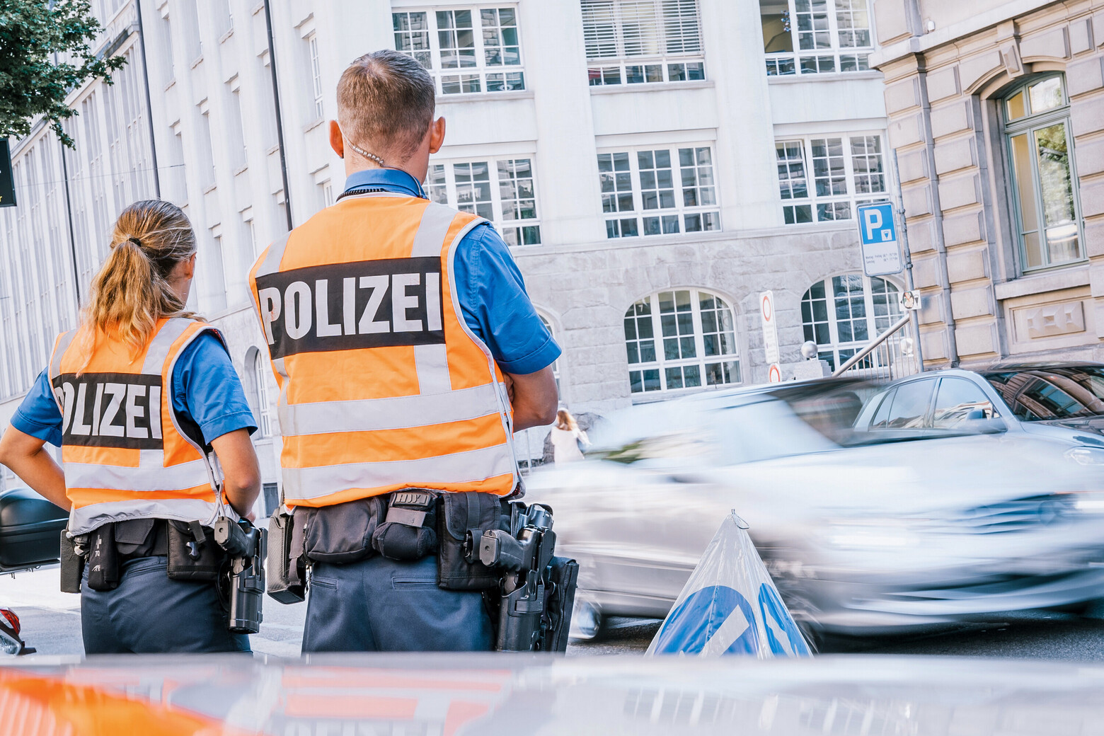 Ein Polizist mit der Polizistin am Strassenrand im Einsatz mit Leuchtweste.