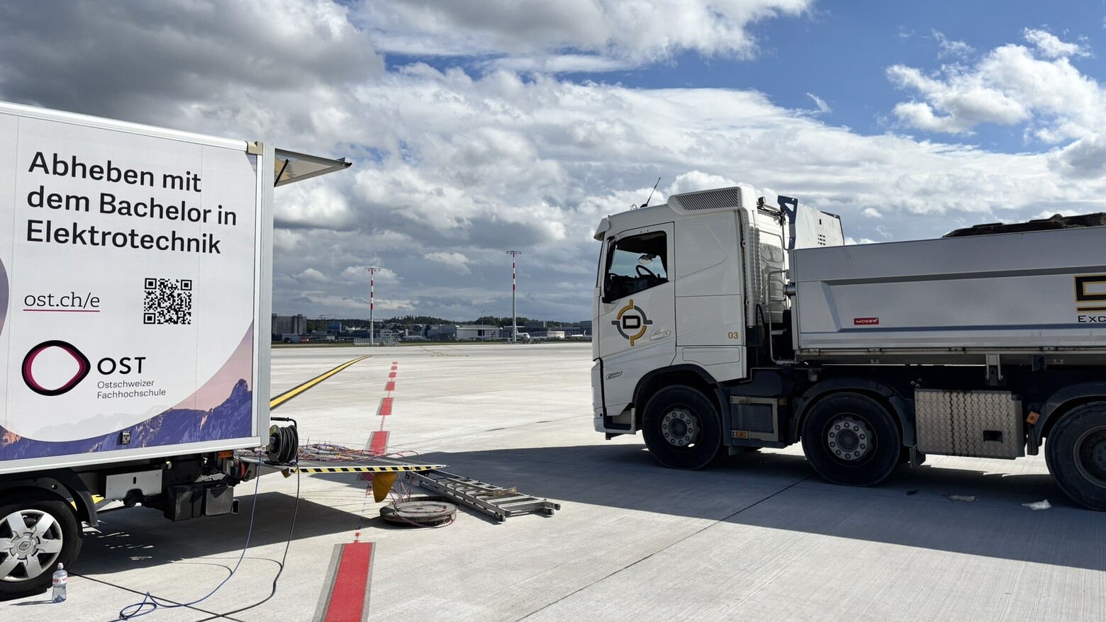 Lastwagen für den Belastungstest auf dem Flugfeld, daneben ein Lieferwagen der OST.