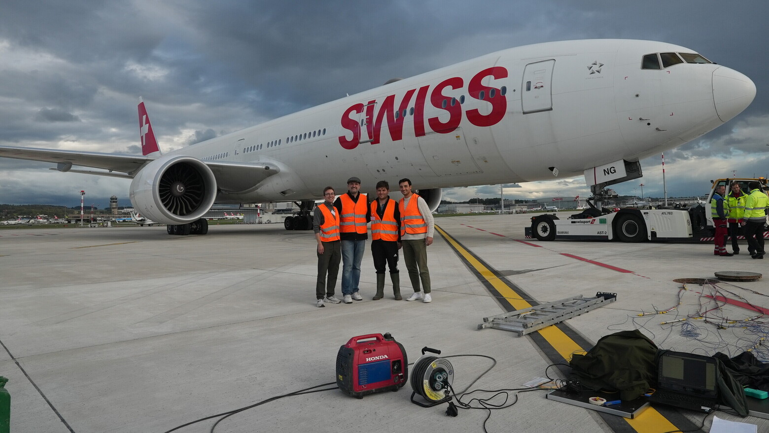 Vier beteiligte OST-Mitarbeiter stehen vor einer Boeing 777 der SWISS auf dem Flugfeld des Flughafens Zürich.
