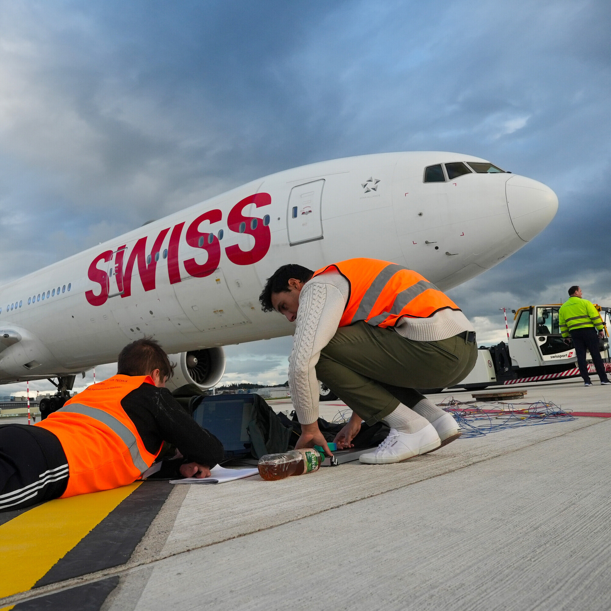 Eine Boeing 777 der SWISS steht auf dem Flugfeld. Zwei Mitarbeiter der OST arbeiten an den Messgeräten.