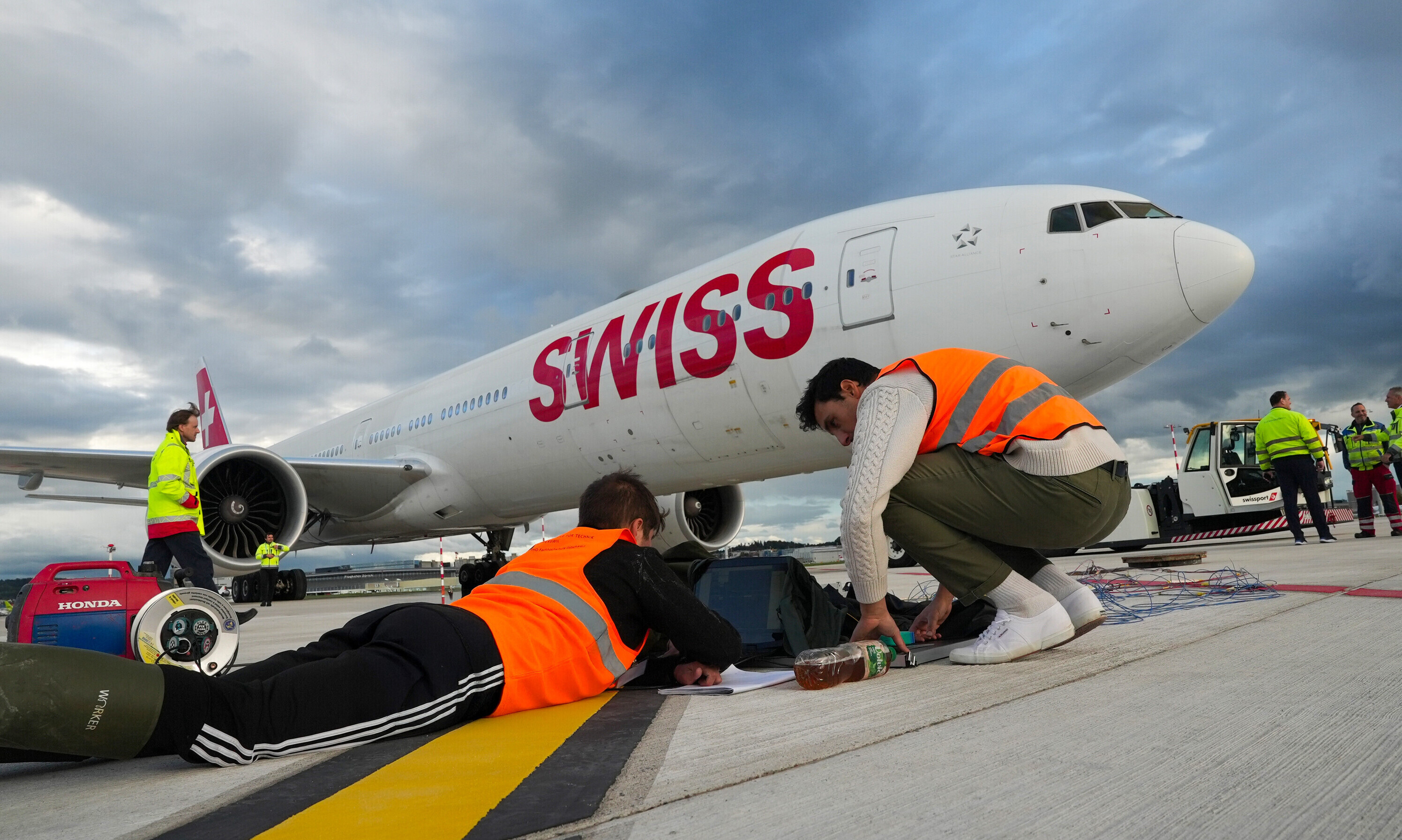 Eine Boeing 777 der SWISS steht auf dem Flugfeld. Zwei Mitarbeiter der OST arbeiten an den Messgeräten.