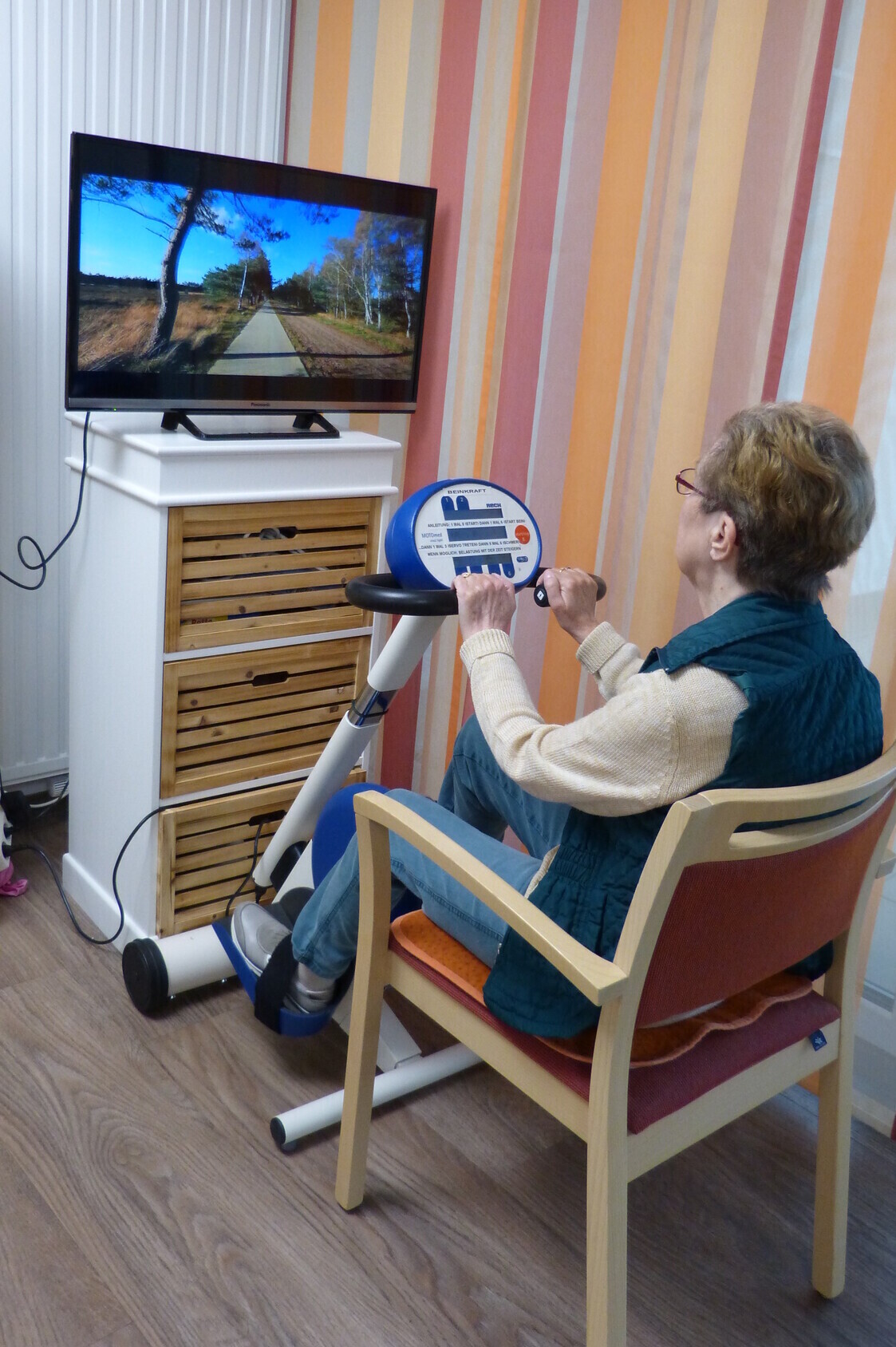 Mit einem Spiel auf dem PC, welcheseine Strasse zeigt, kann die Bewohnerin auf dem Stuhl davor mit dem Gerät versuchen zu lenken.