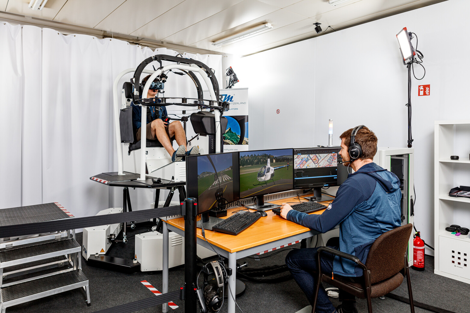 Ein Flugsimulator der VRMotion AG wird auf Herz und Nieren geprüft: Ein Mann sitzt im Simulator, ein weiterer vor mehreren Bildschirmen.