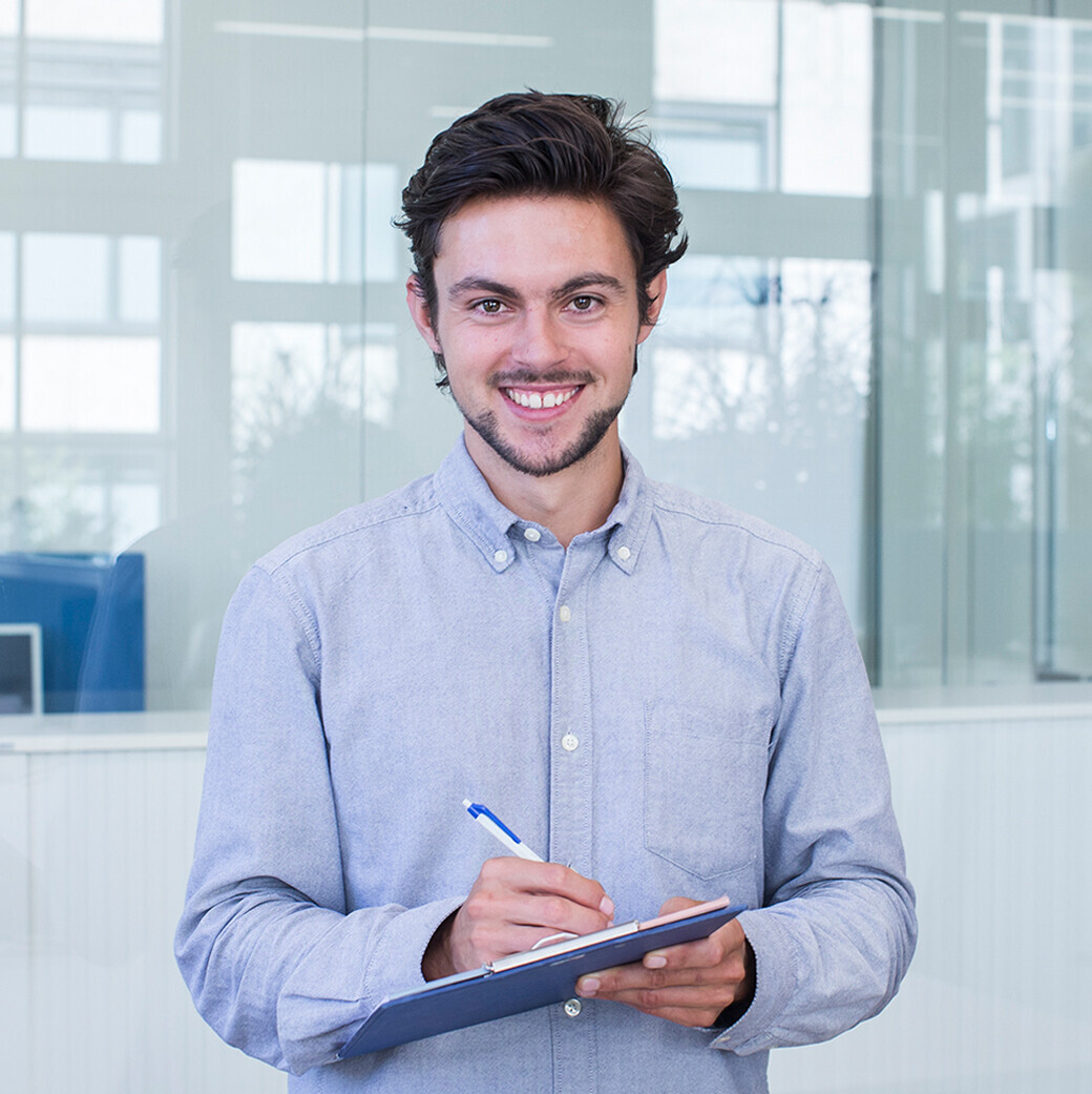 Dominik Züttel hat an der OST Wirtschaftsinformatik studiert, er hält einen Stift und ein Klemmbrett in der Hand. 