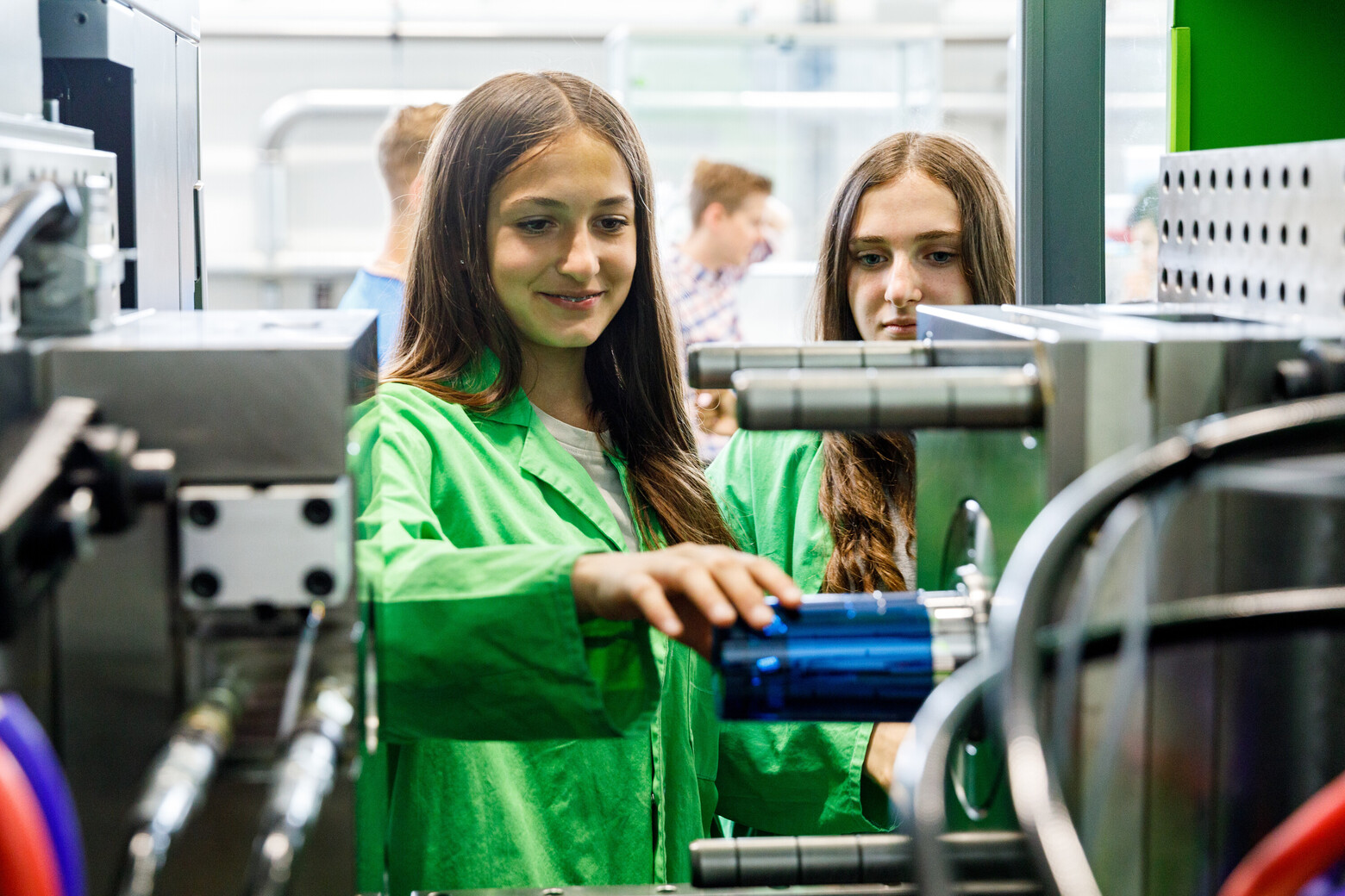 Eine Schülerin entnimmt einen gerade produzierten Becher direkt aus der Spritzgussmaschine.