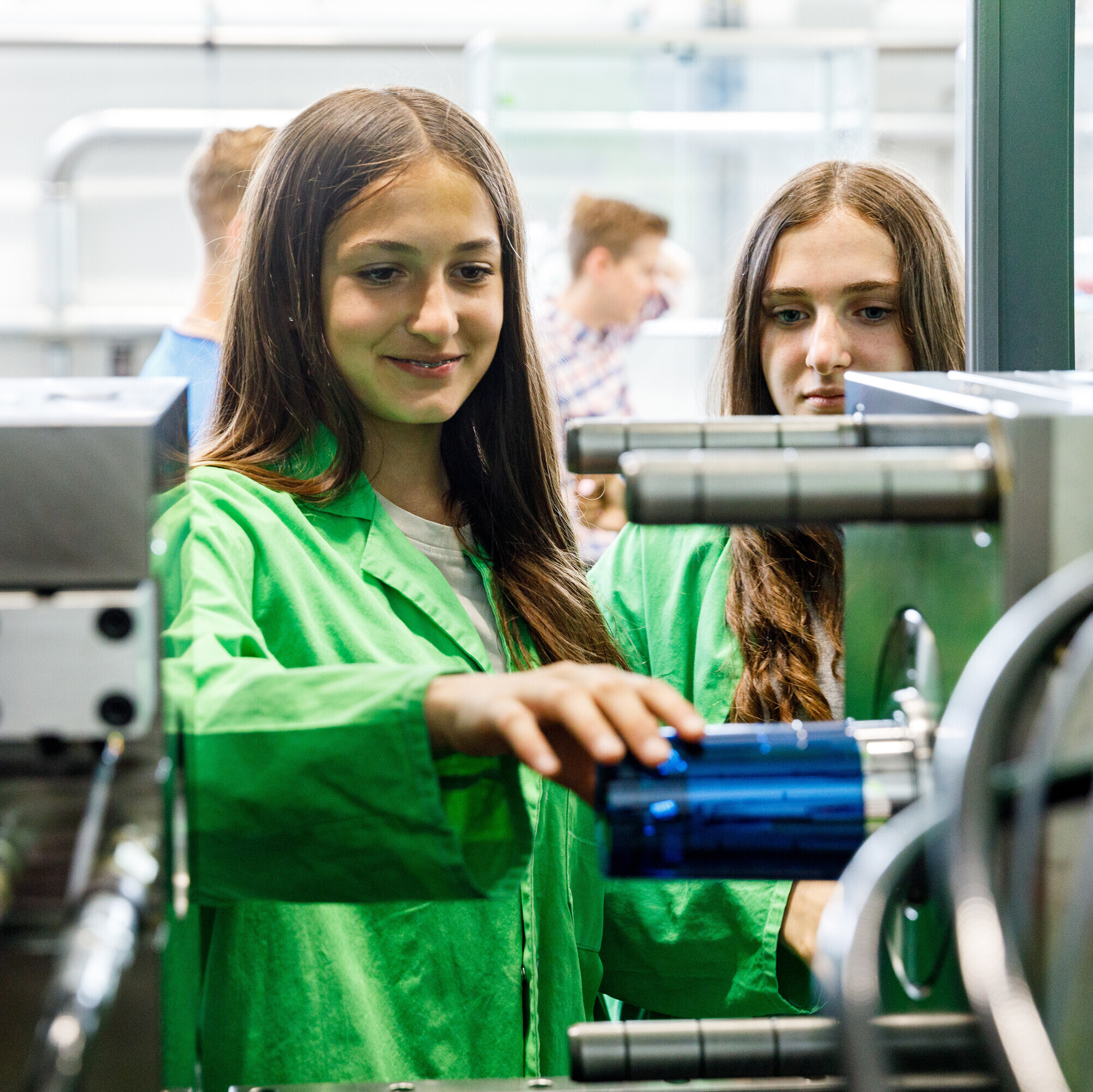 Eine Schülerin entnimmt einen gerade produzierten Becher direkt aus der Spritzgussmaschine.