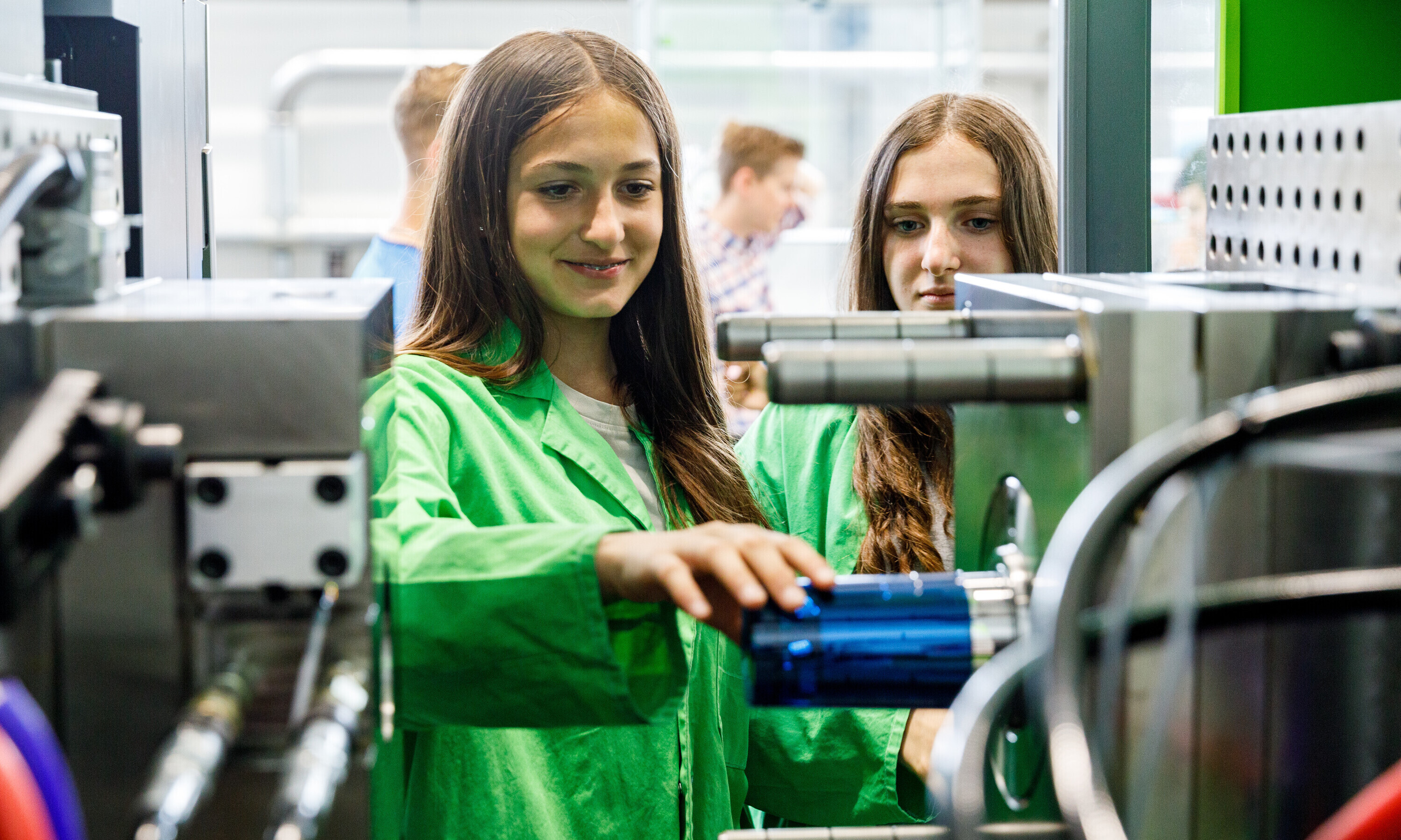 Eine Schülerin entnimmt einen gerade produzierten Becher direkt aus der Spritzgussmaschine.