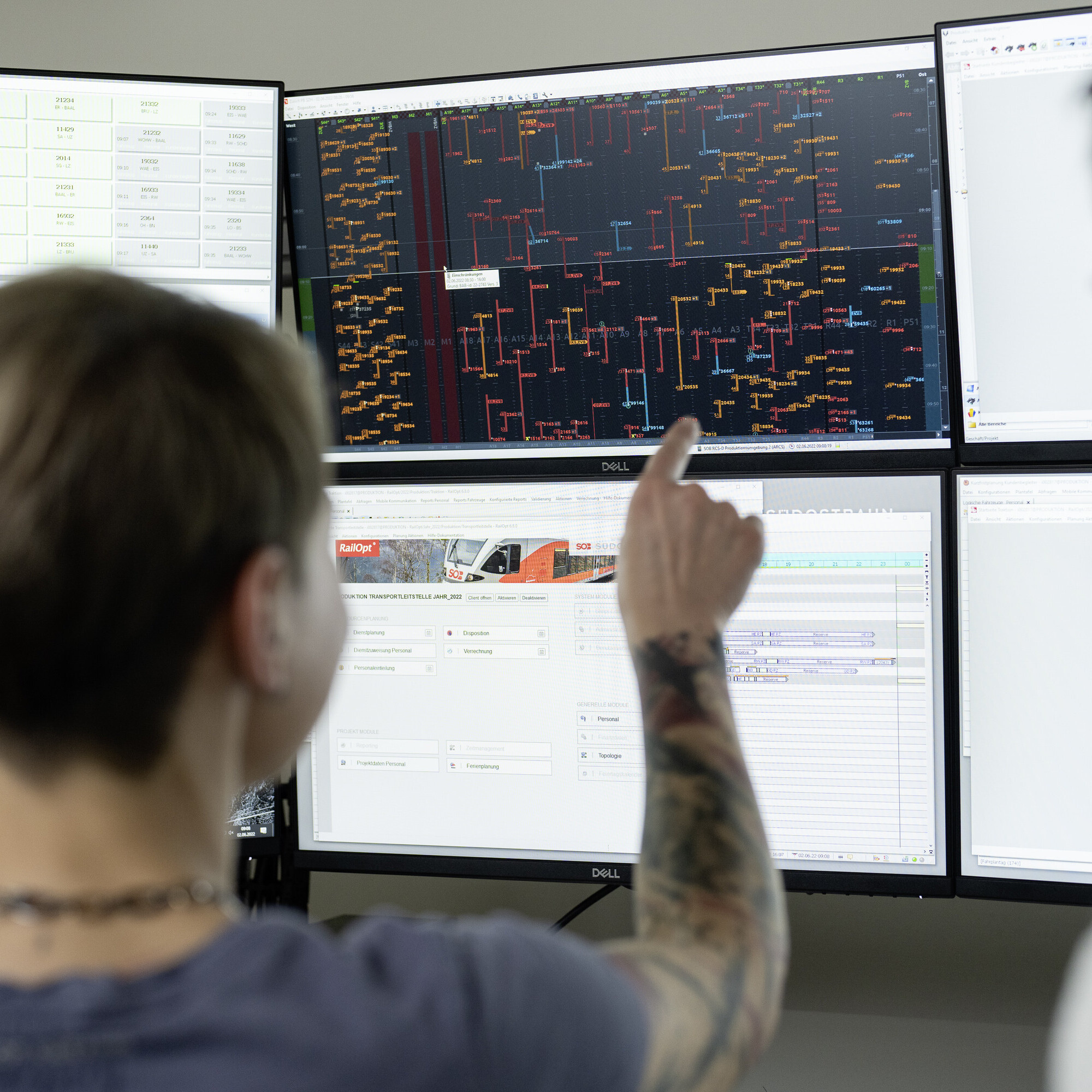  In der SOB-Betriebszentrale in Herisau zeigt eine Person auf einen der sechs Bildschirme. Zu sehen ist jedes Gleis, jede Weiche und jedes Fahrzeug, das auf dem Schienennetz verkehrt.