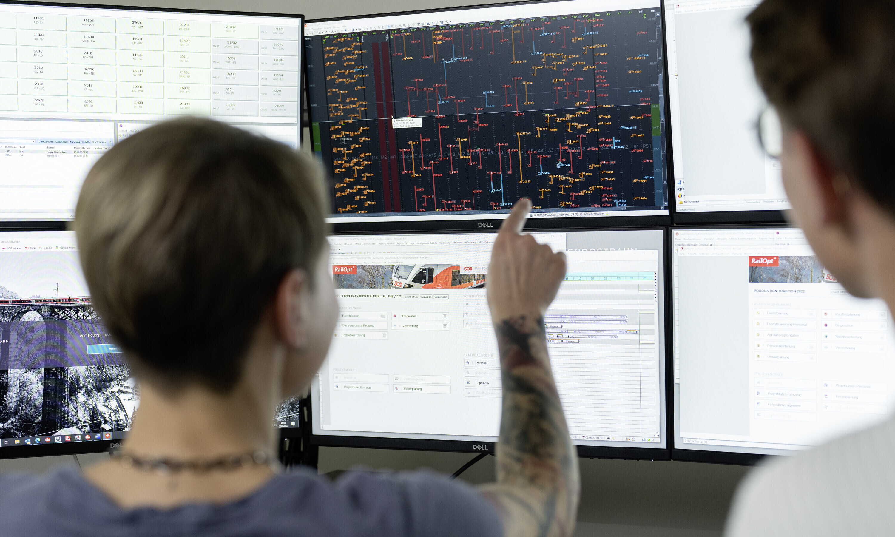  In der SOB-Betriebszentrale in Herisau zeigt eine Person auf einen der sechs Bildschirme. Zu sehen ist jedes Gleis, jede Weiche und jedes Fahrzeug, das auf dem Schienennetz verkehrt.