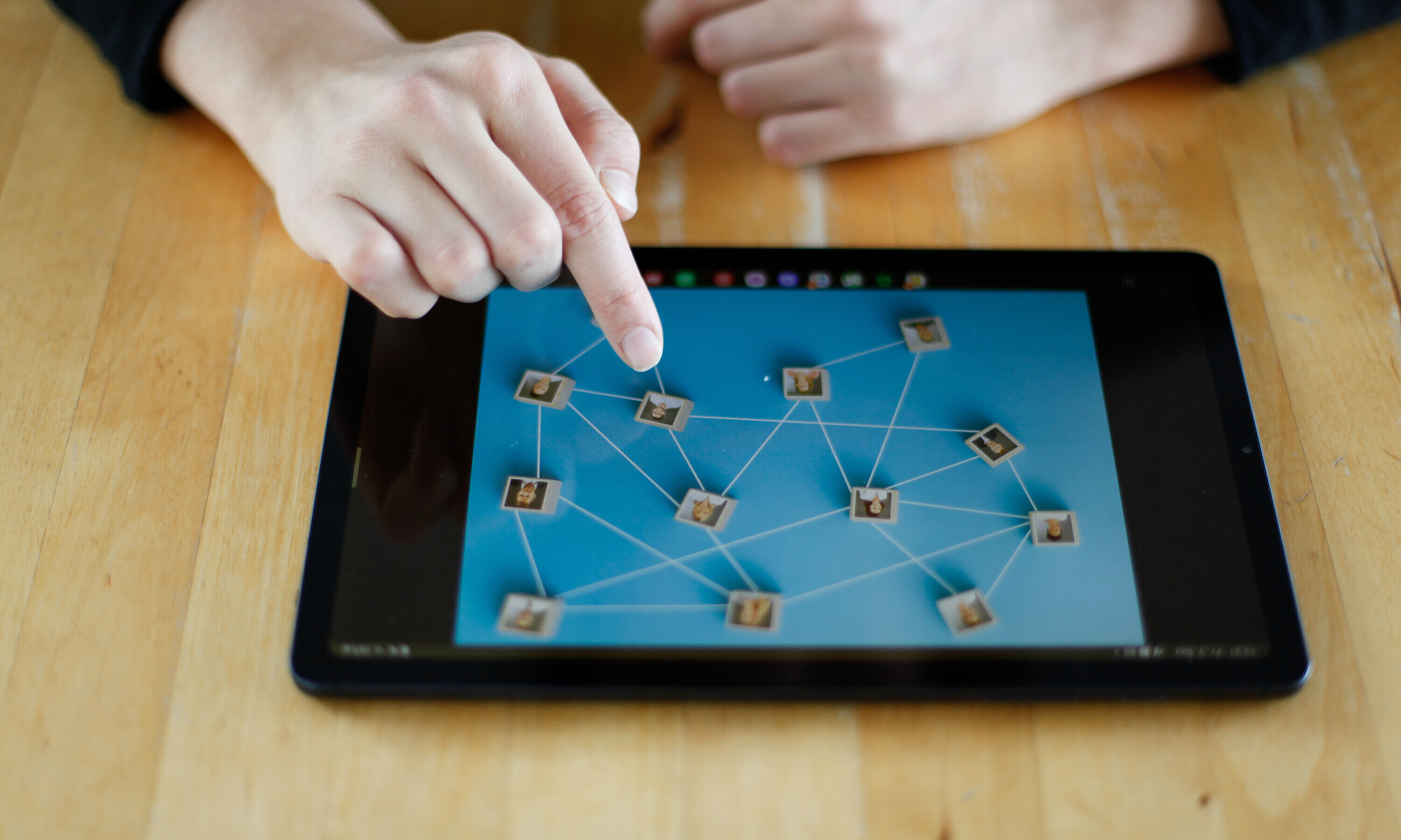 Das iPad liegt auf einem Tisch. Eine Hand tippt darauf, um die Organisationsstruktur aus HR-Sicht zu analysieren.