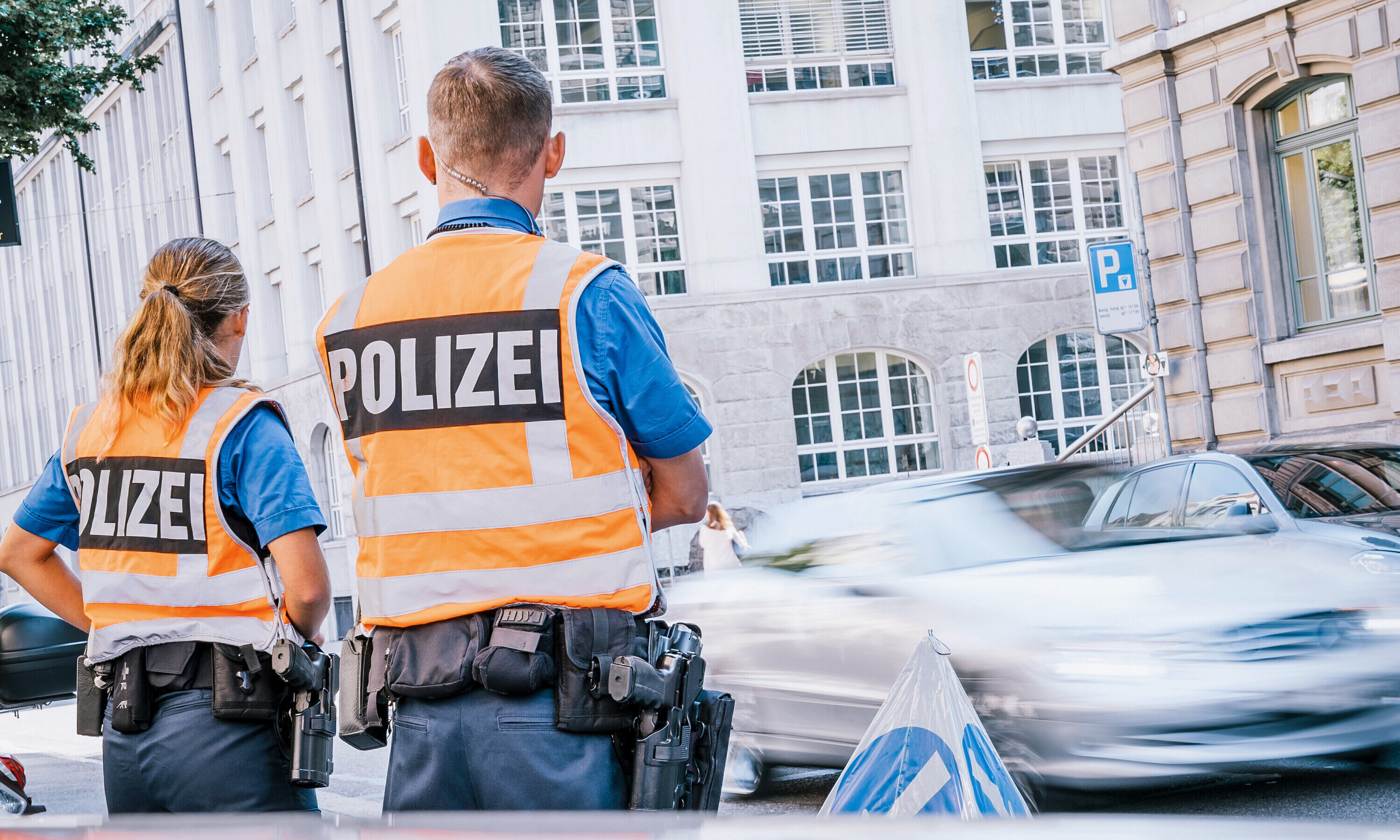 Ein Polizist mit der Polizistin am Strassenrand im Einsatz mit Leuchtweste.