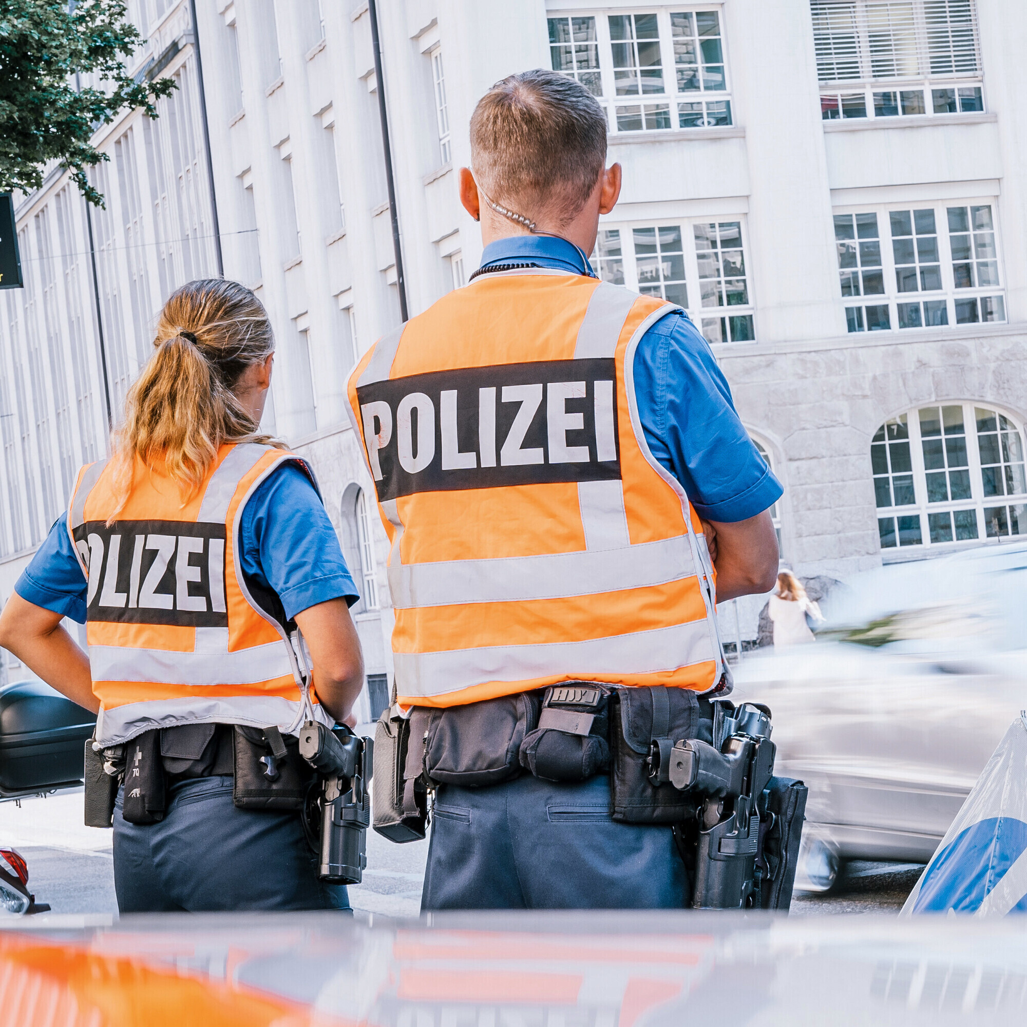 Ein Polizist mit der Polizistin am Strassenrand im Einsatz mit Leuchtweste.
