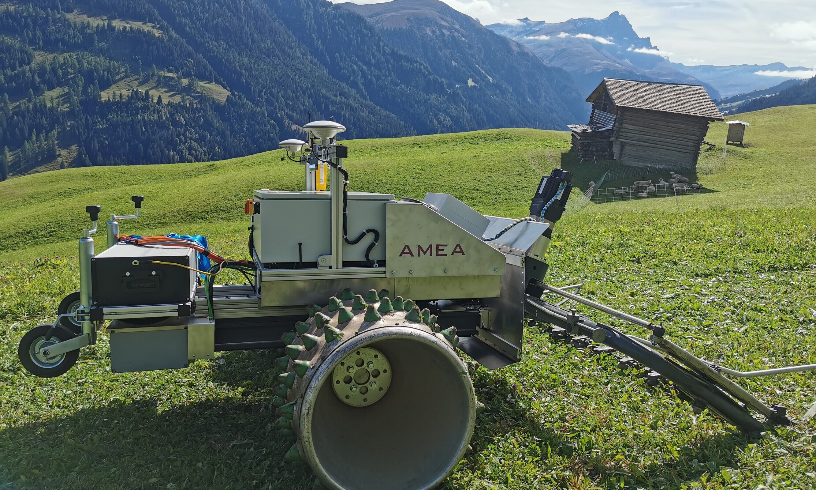 Auf einer Wiese in den Schweizer Alpen steht ein Mähroboter, er soll den Bergbauern die Arbeit erleichtern.
