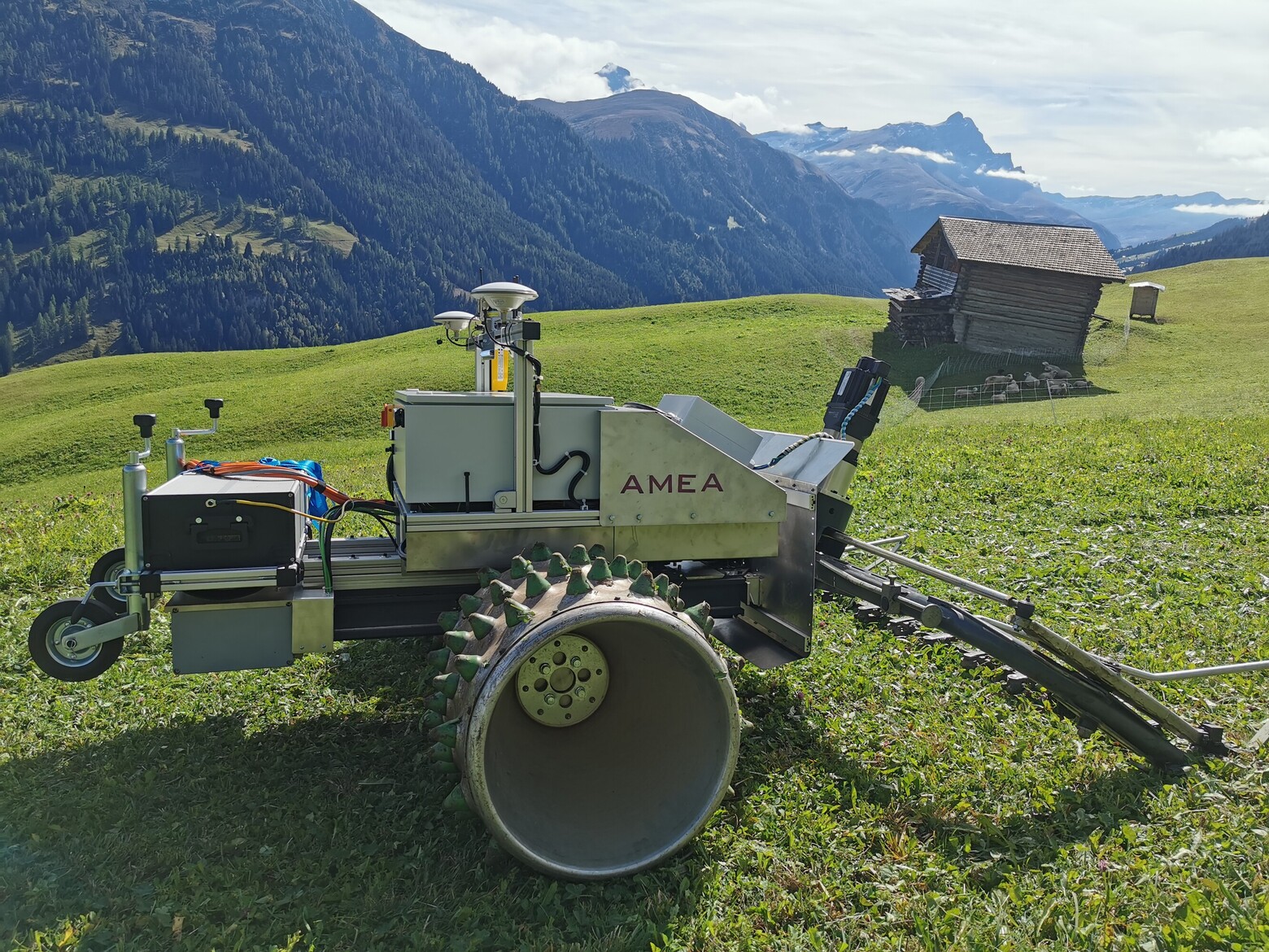 Auf einer Wiese in den Schweizer Alpen steht ein Mähroboter, er soll den Bergbauern die Arbeit erleichtern.