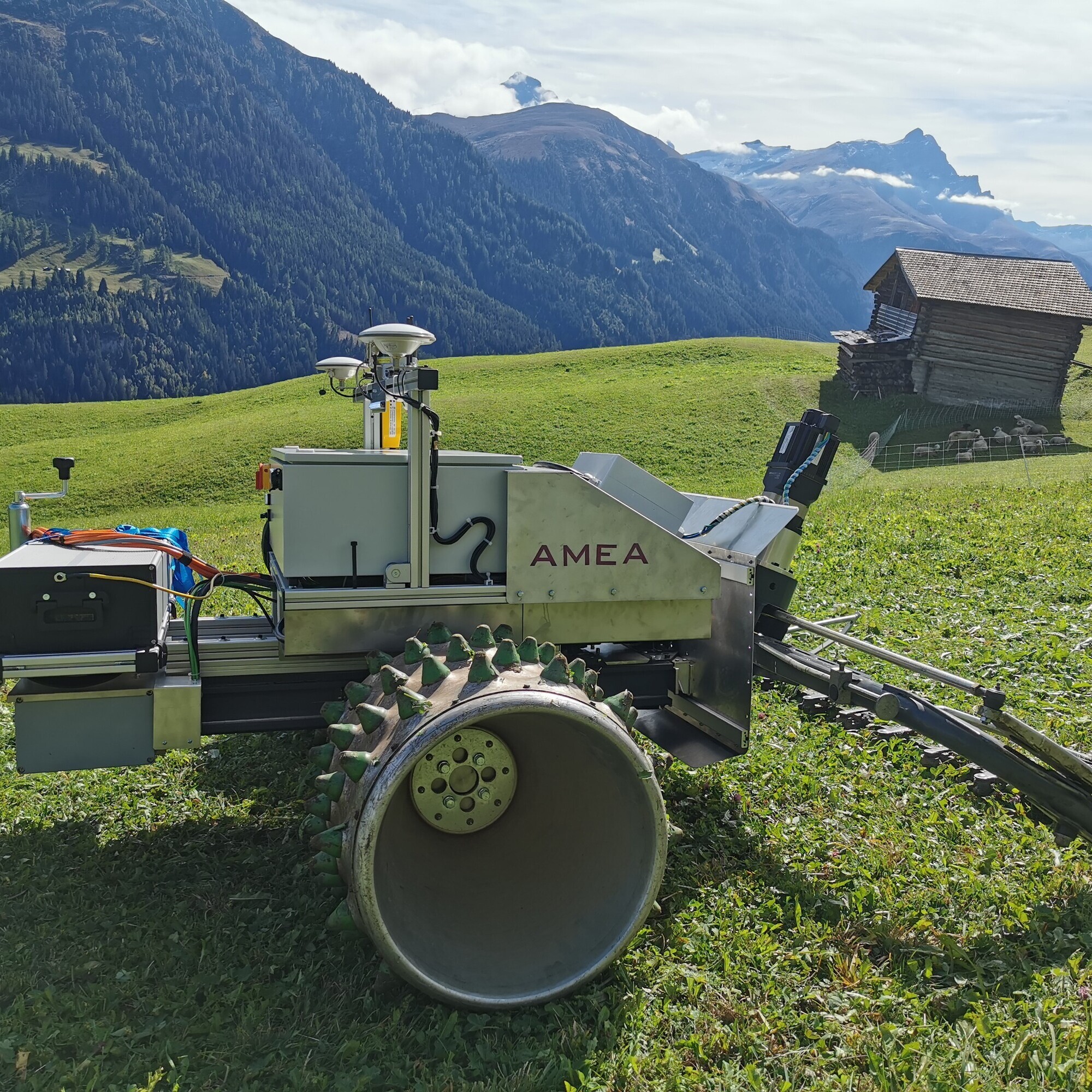 Auf einer Wiese in den Schweizer Alpen steht ein Mähroboter, er soll den Bergbauern die Arbeit erleichtern.