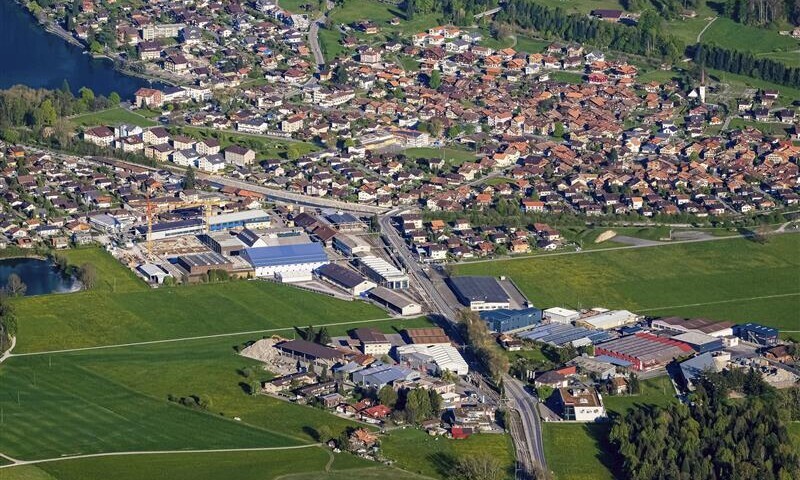Eine an einen See grenzende Siedlung mit Industrieanlagen aus der Vogelperspektive.