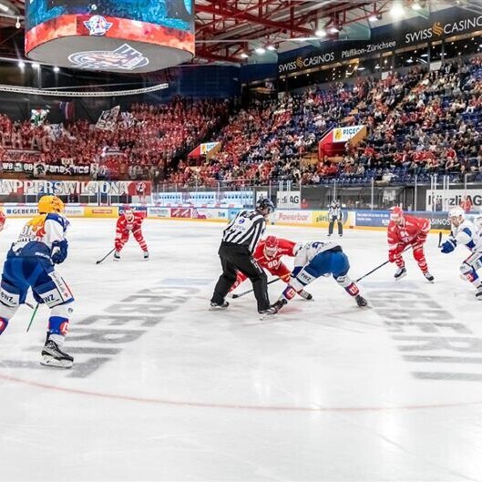 Hier ist der Eishockeyclub Rapperswil-Jona auf dem Spielfeld der vollen St.Galler Kantonalbank Arena zu sehen.