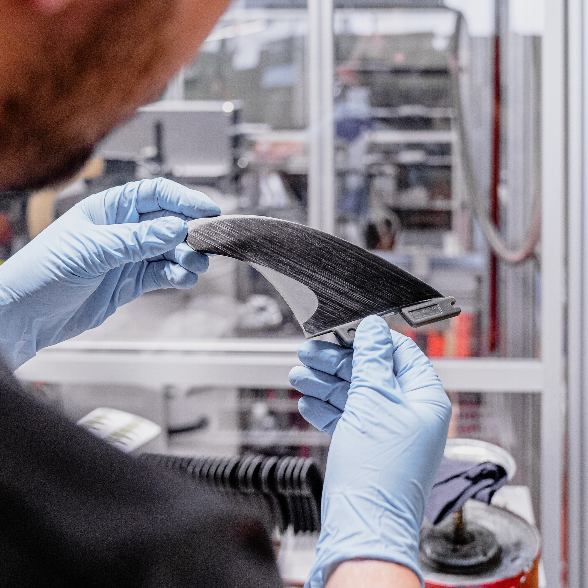 Auf dem Bild ist eine fast fertige Surffinne in den Händen des Produzenten zu sehen.