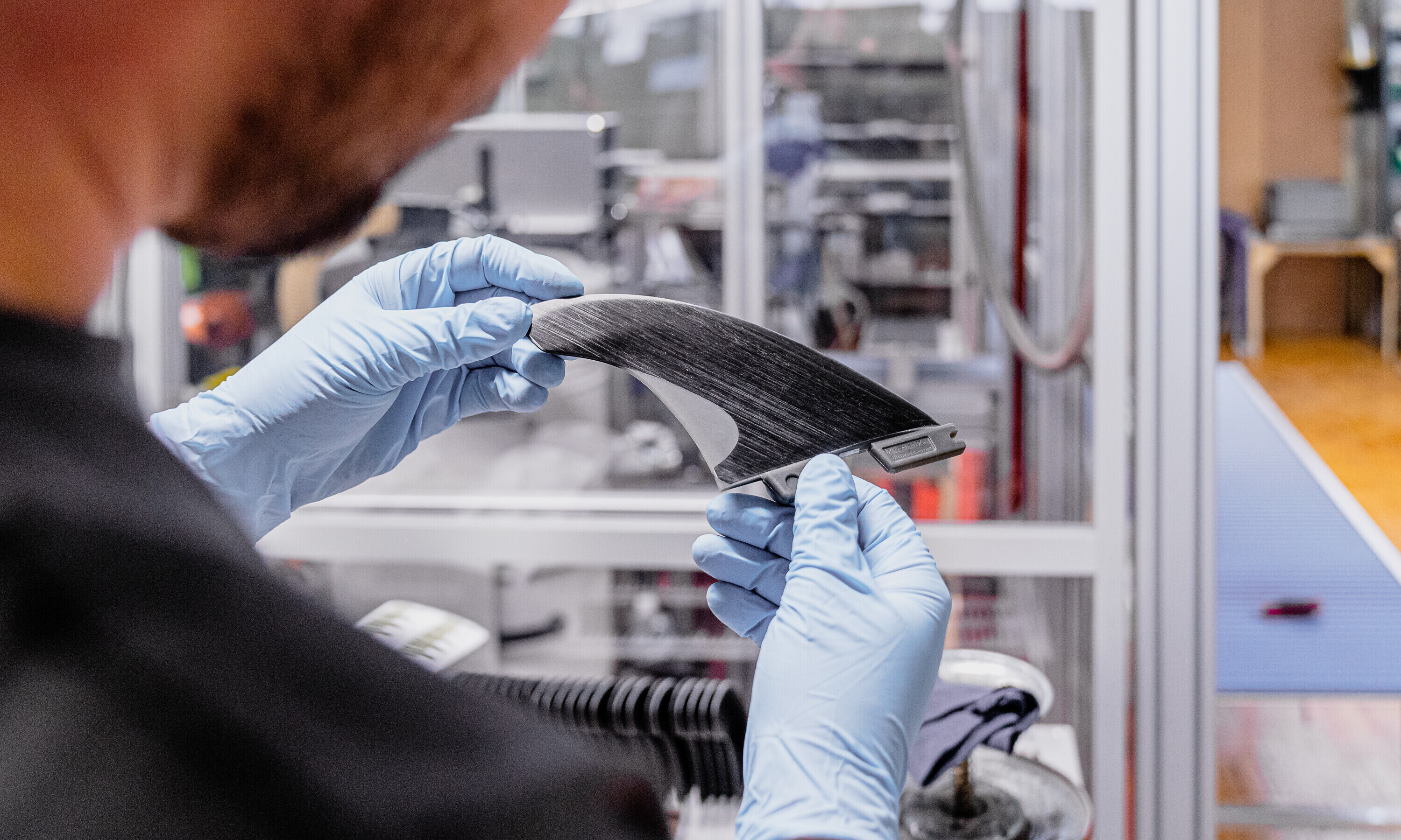 Auf dem Bild ist eine fast fertige Surffinne in den Händen des Produzenten zu sehen.