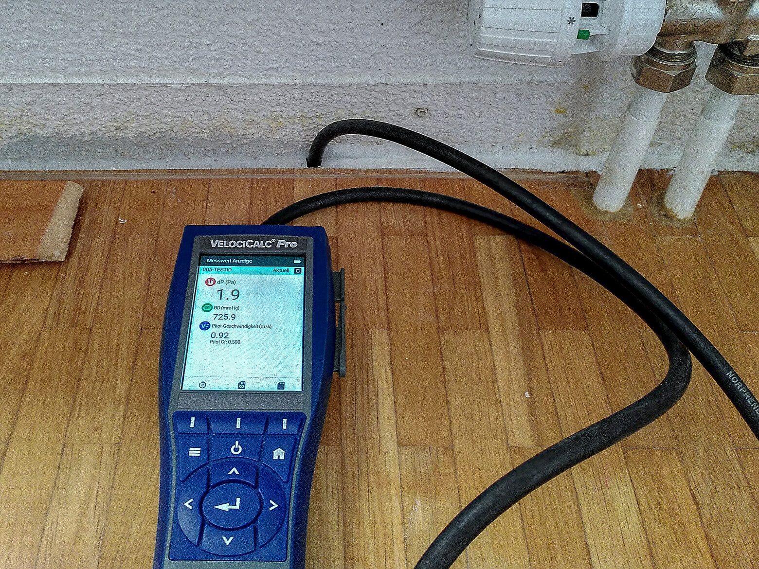 Das kleine blaue Gerät ist hier auf dem Fussboden unterhalb eines Heizungsradiators angebracht, um den Geruch zu finden.