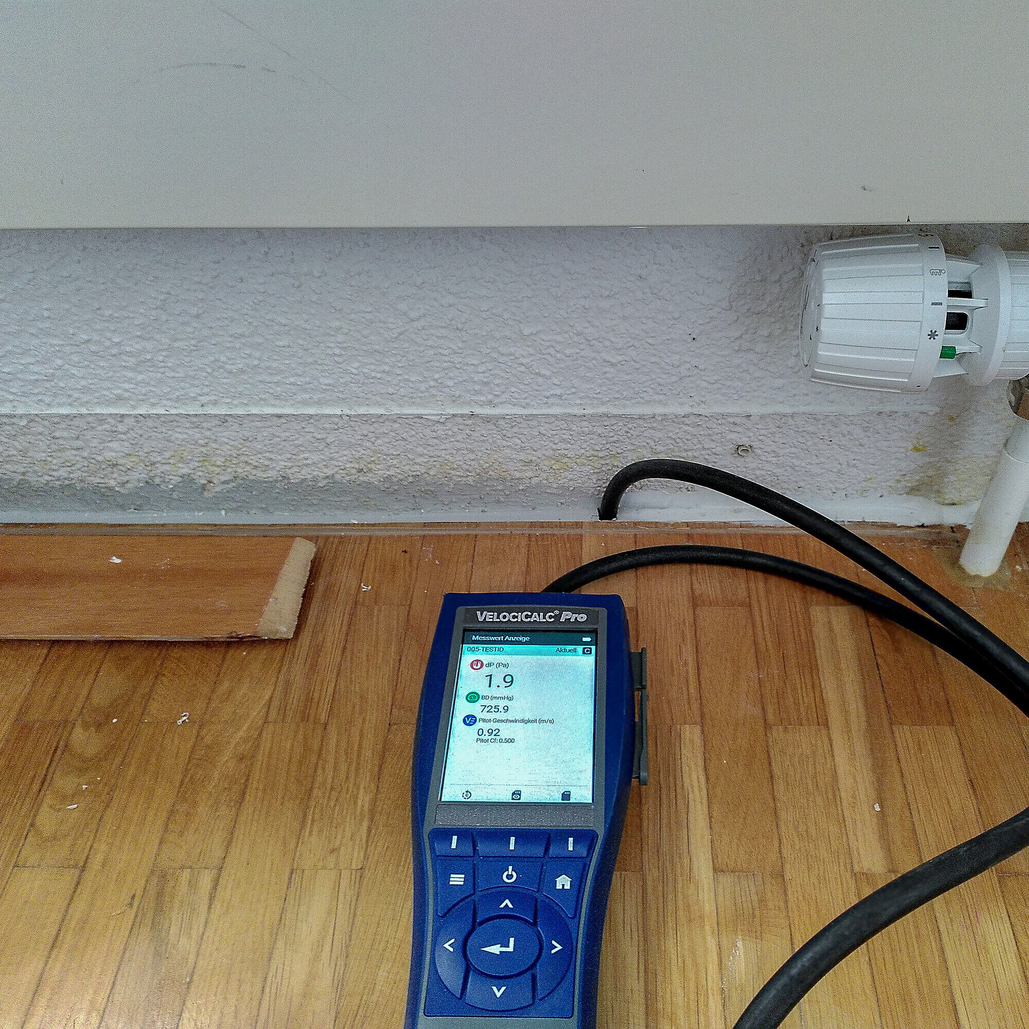 Das kleine blaue Gerät ist hier auf dem Fussboden unterhalb eines Heizungsradiators angebracht, um den Geruch zu finden.  