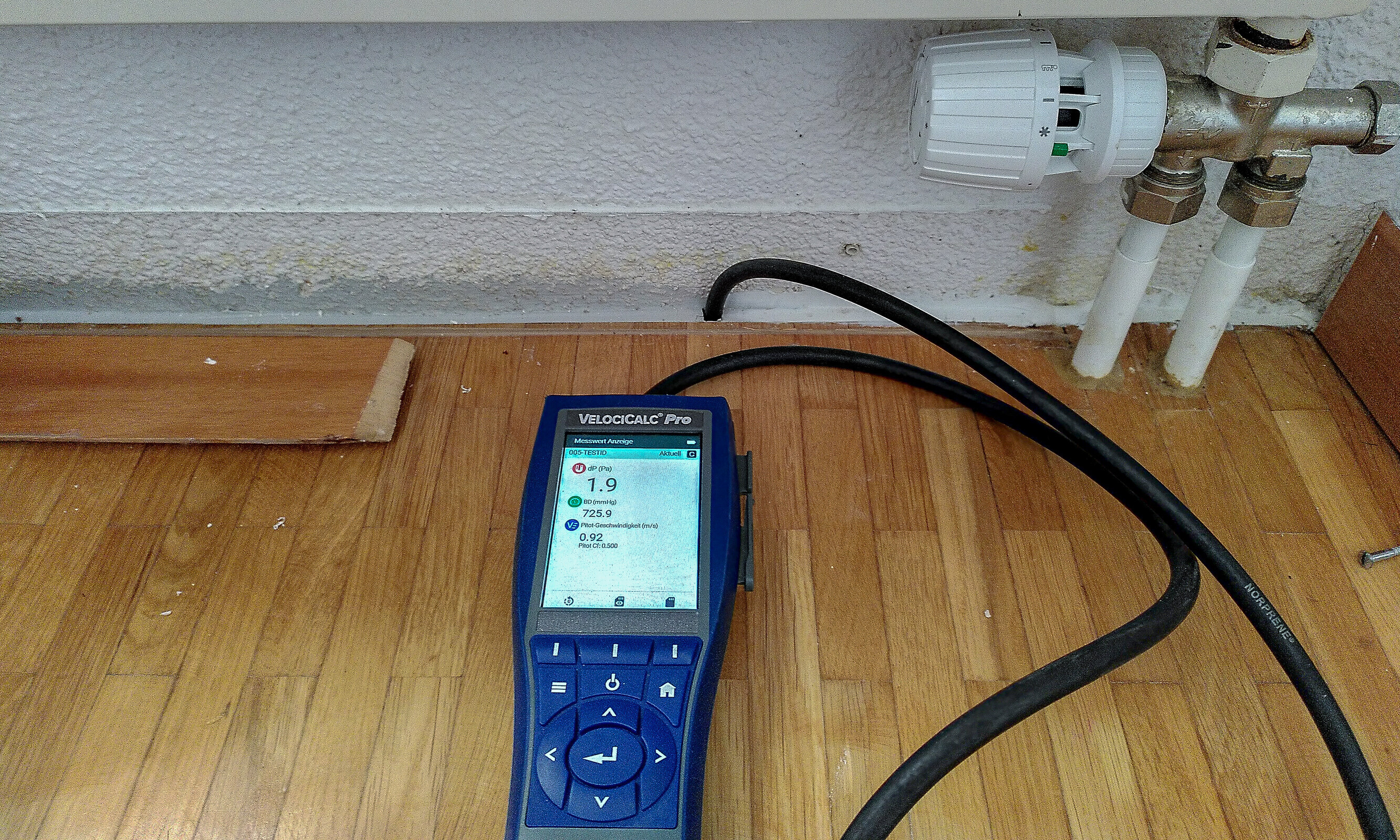 Das kleine blaue Gerät ist hier auf dem Fussboden unterhalb eines Heizungsradiators angebracht, um den Geruch zu finden.