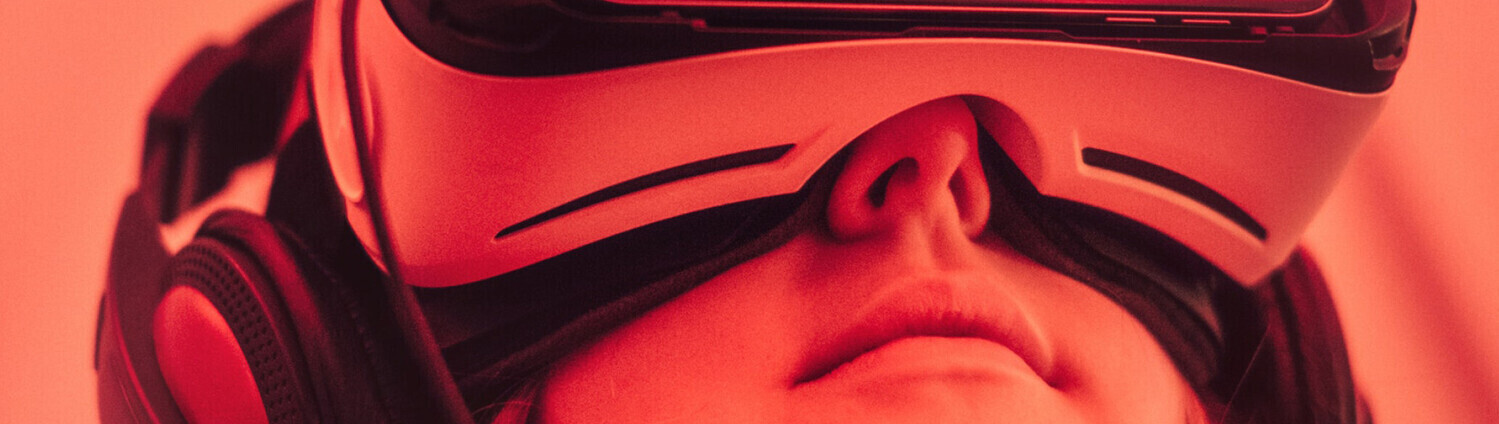 Eine junge Frau trägt eine VR-Brille. Das Bild ist rot eingefärbt.