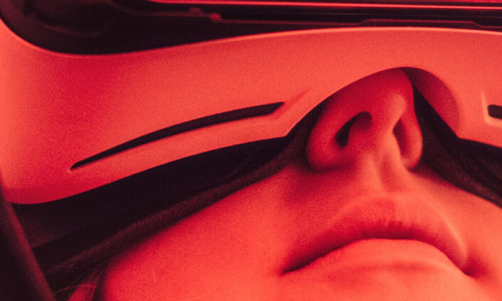 Eine junge Frau trägt eine VR-Brille. Das Bild ist rot eingefärbt.