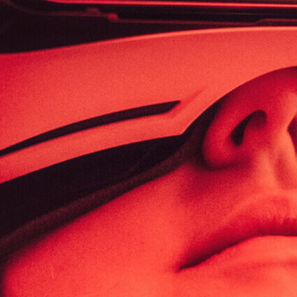 Eine junge Frau trägt eine VR-Brille. Das Bild ist rot eingefärbt.