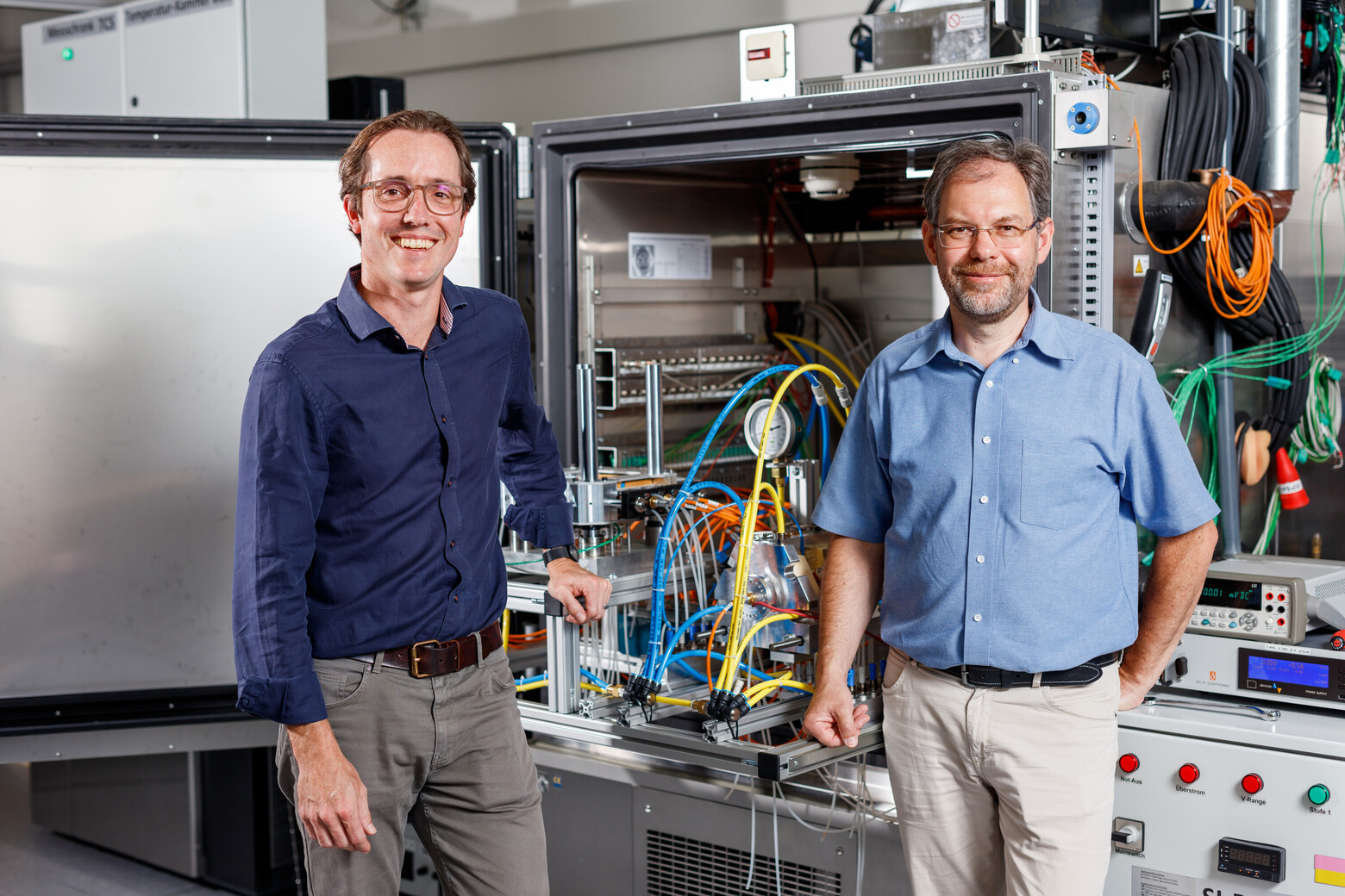Hier sieht man links im Bild Rouven Christen und rechts Dr. Gerhard Rizzo vor einer ihrer Versuchseinheiten im Batterielabor in Buchs.