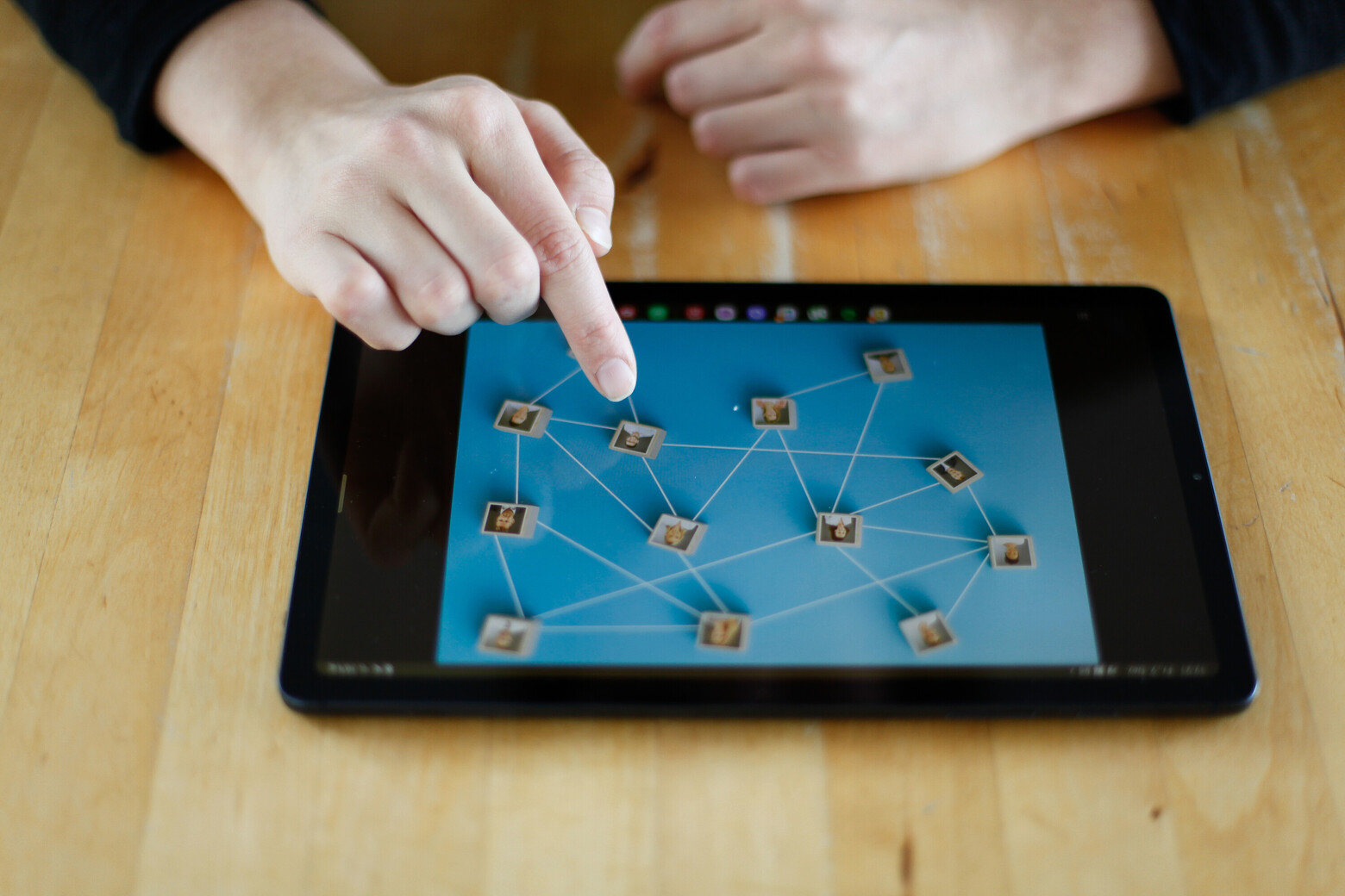 Das iPad liegt auf einem Tisch. Eine Hand tippt darauf, um die Organisationsstruktur aus HR-Sicht zu analysieren.