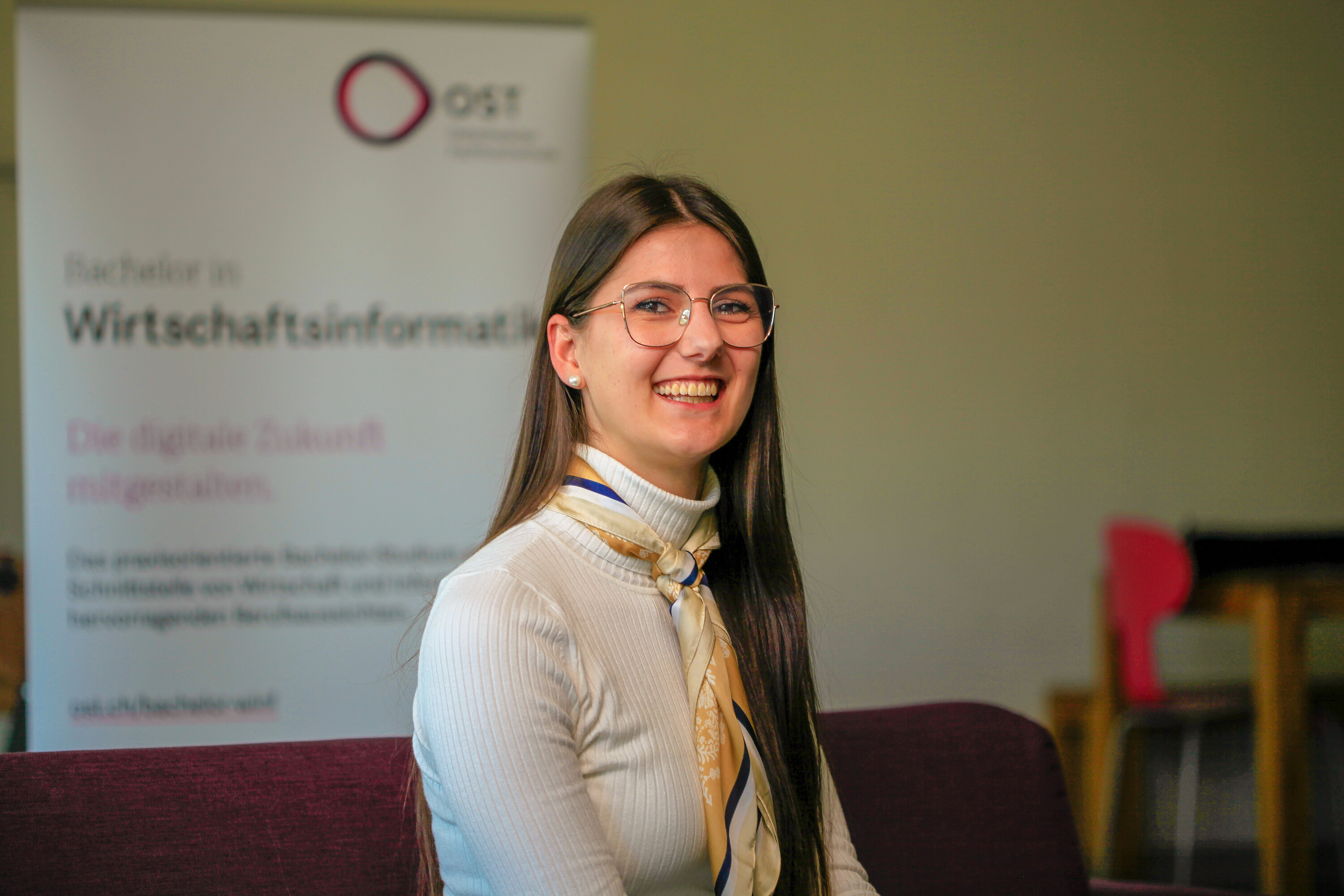Maria Näf, eine junge Frau vor einem Banner, studiert Wirtschaftsinformatik an der OST.