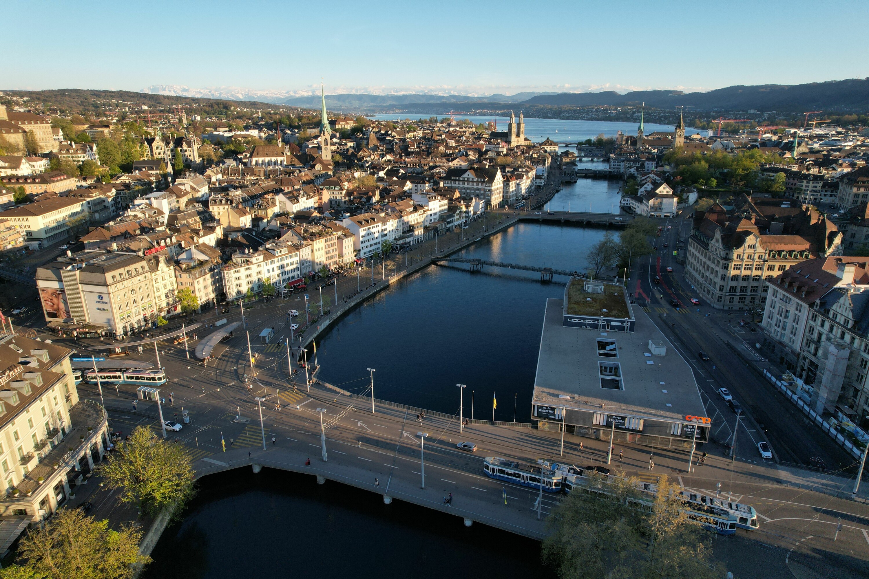 Aerial view of Zurich with historic architecture and mountain backdrop. OST-Reallabor in Zürich erforscht nachhaltige Massnahmen zur Ressourcenschonung und sozialen sowie ökologischen Auswirkungen.