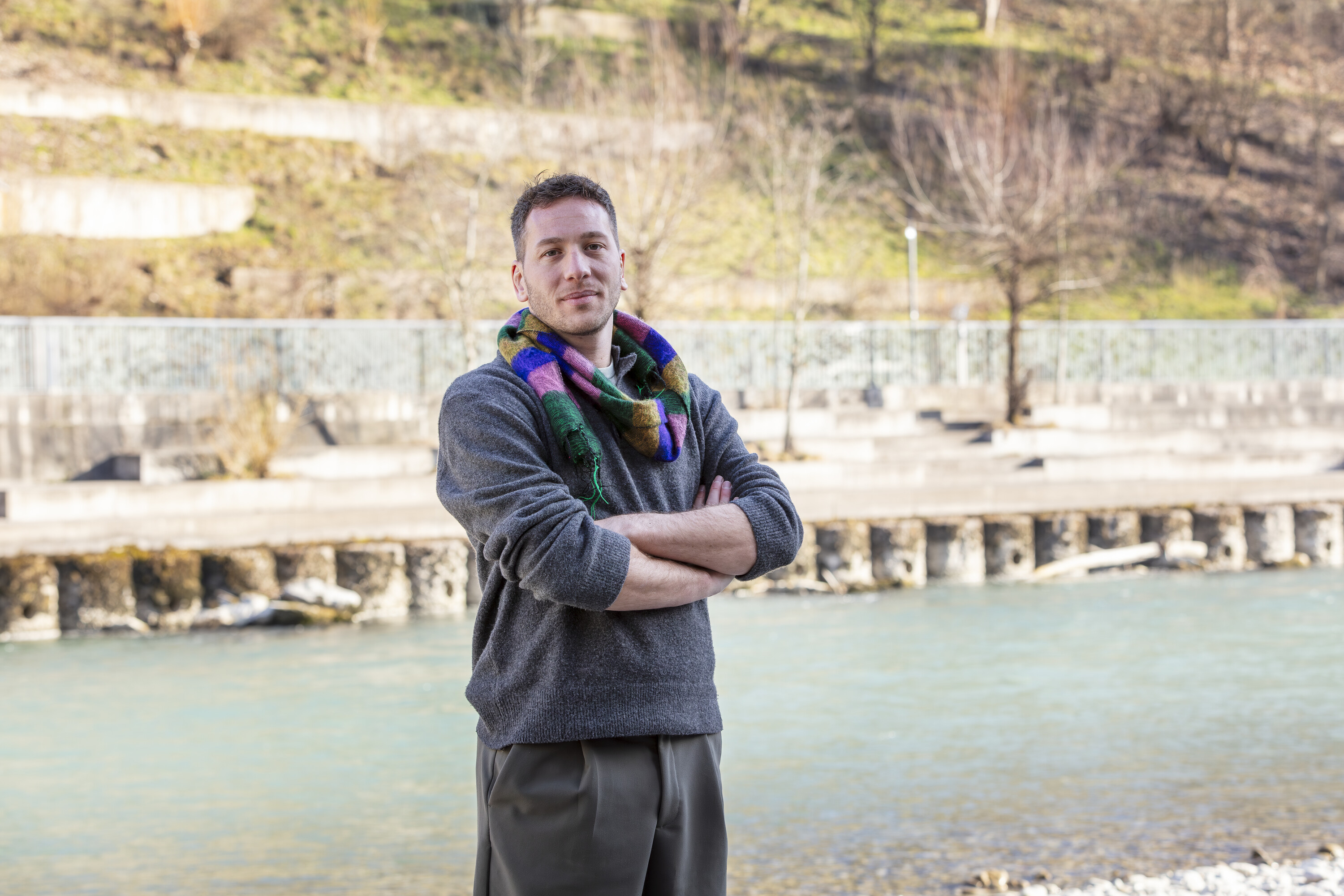 Marco Lehmann steht mit verschränkten Armen vor einem Fluss in karger Winterlandschaft.